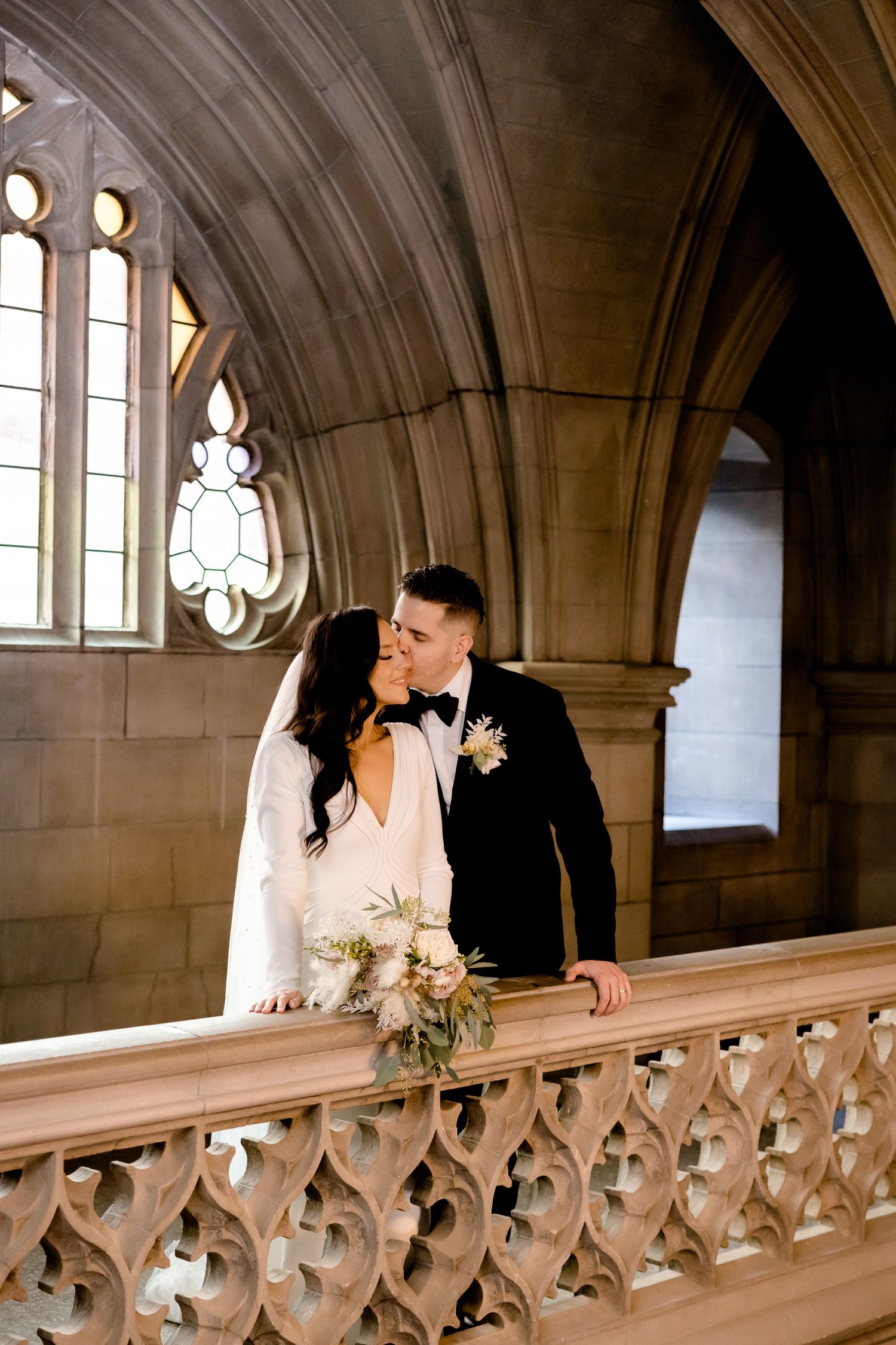 Elegant wedding moment captured against Gothic windows and stone architectural details.