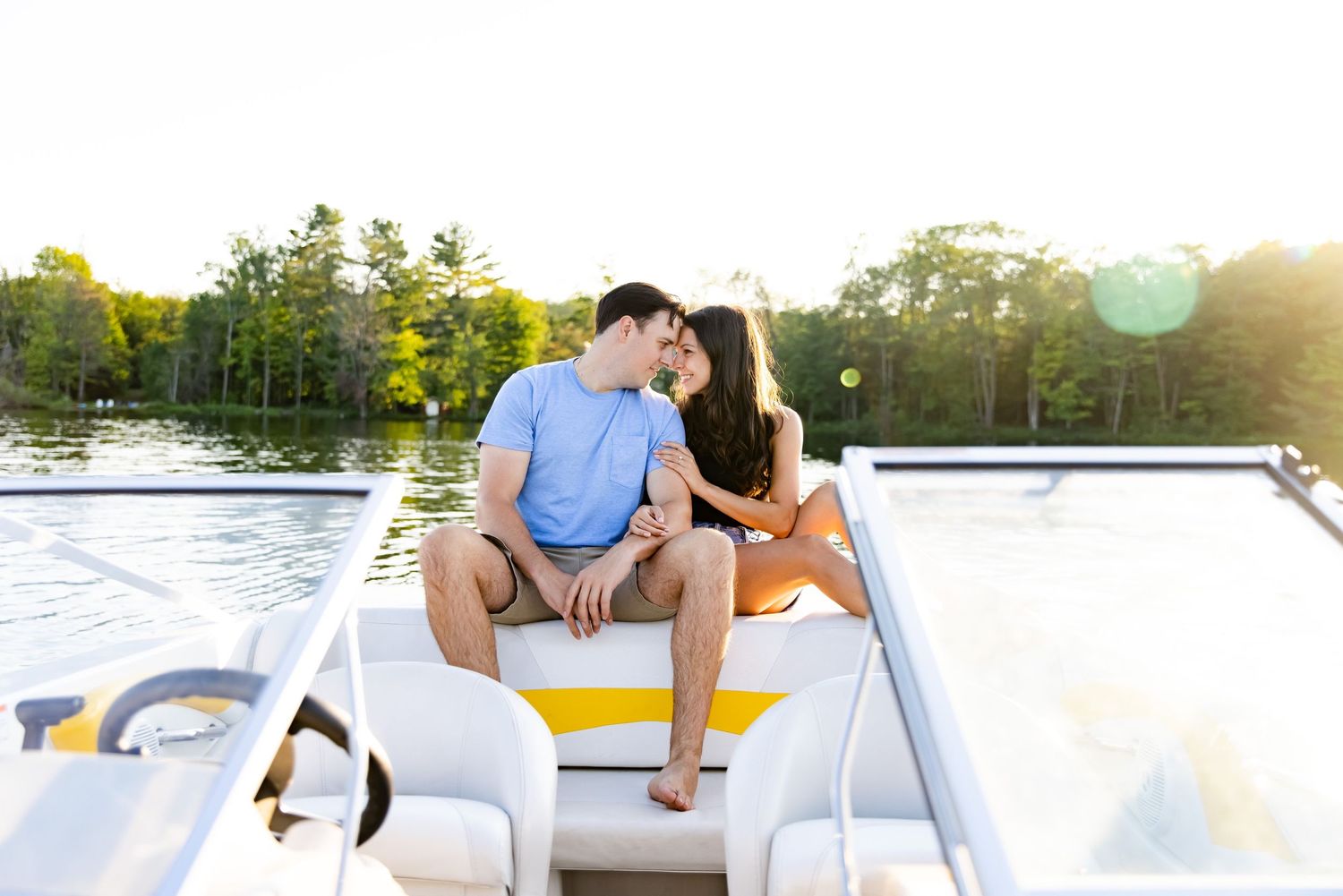 Couple enjoying a sunset boat ride together on a lake surrounded by trees.