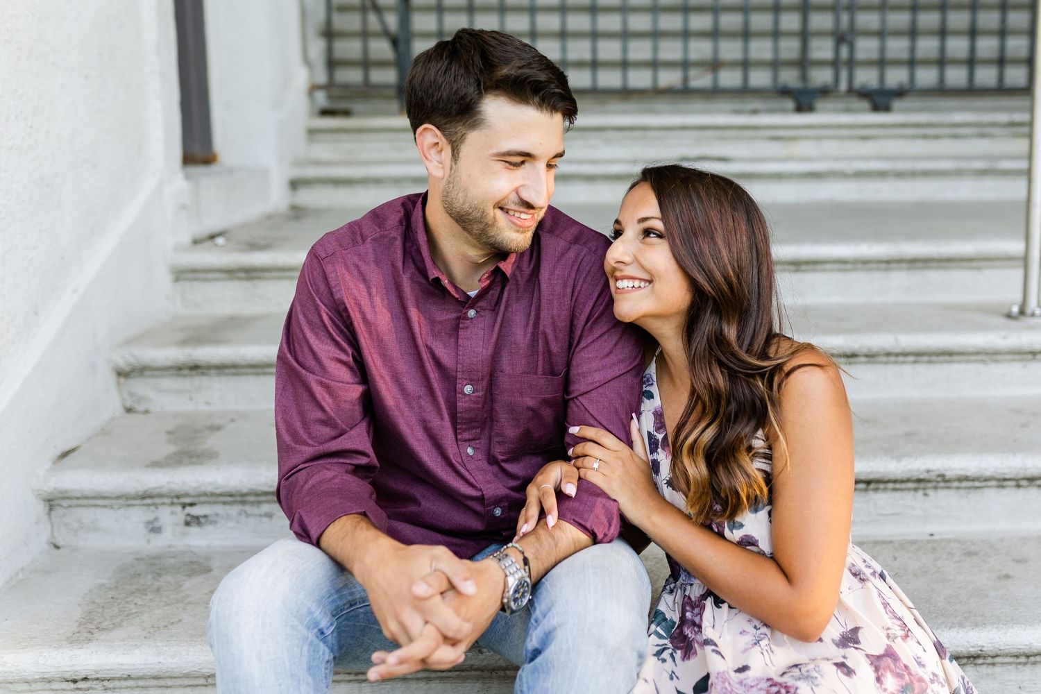 Joyful couple laughing together while sitting on concrete steps outdoors.