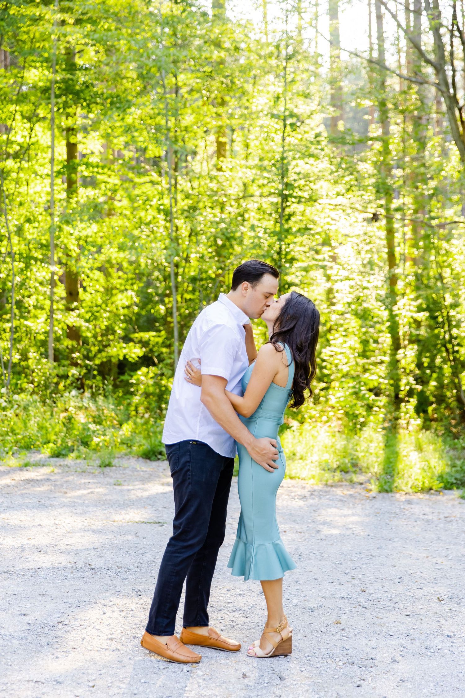 Romantic couple sharing an intimate moment on a sunny forest path.