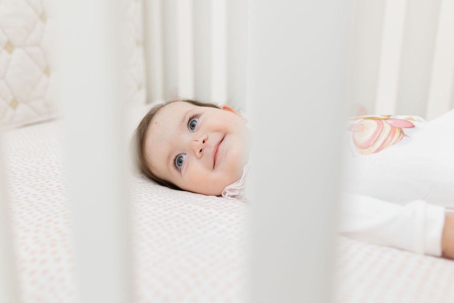 White crib bars framing a gentle nursery scene.
