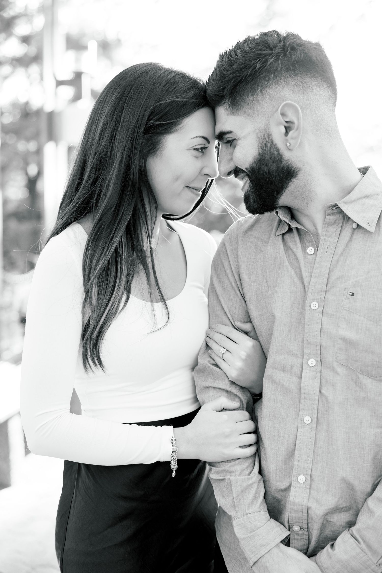A black and white portrait capturing an intimate moment between a couple outdoors.
