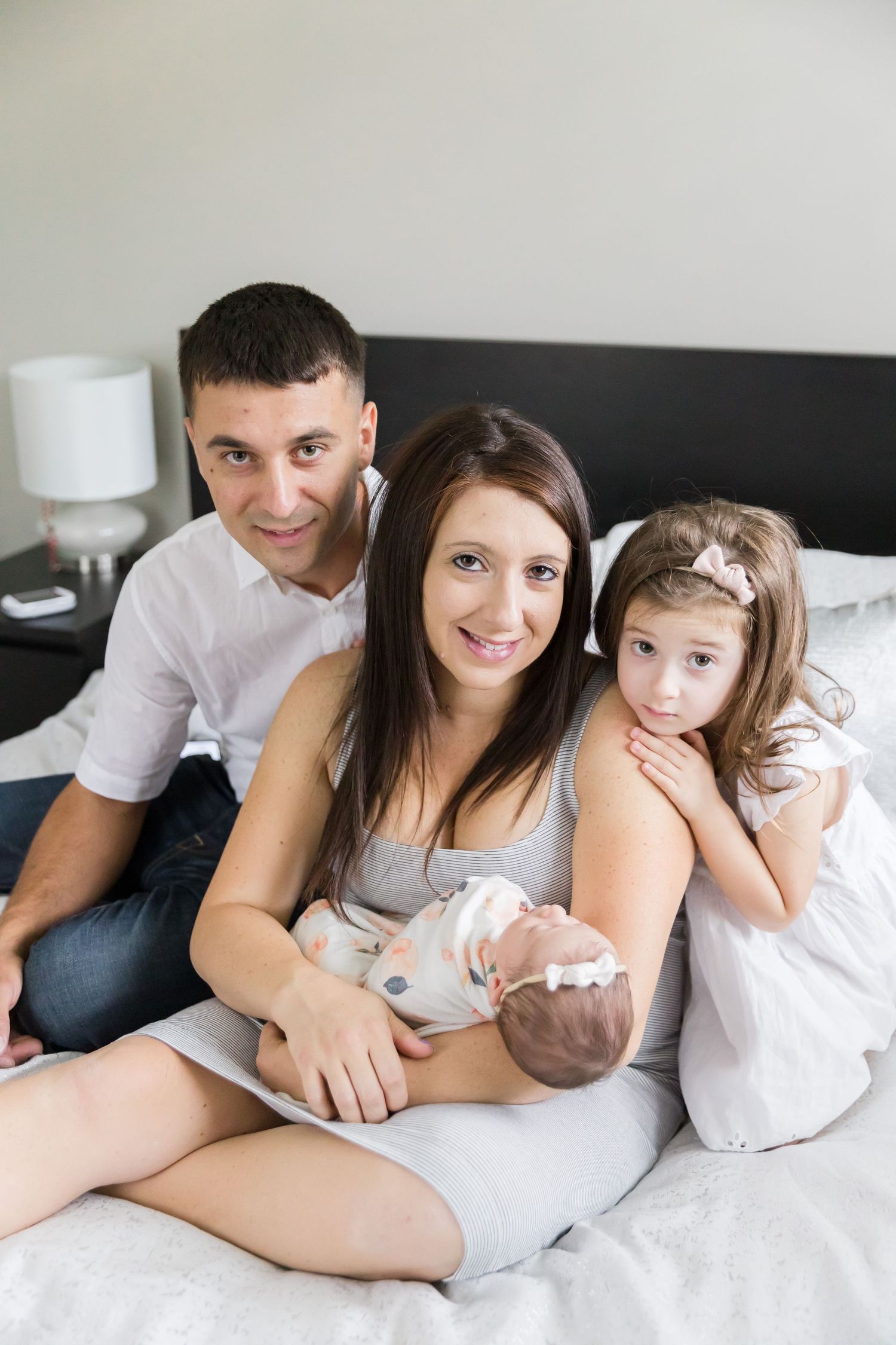 Family portrait on bed with newborn baby.