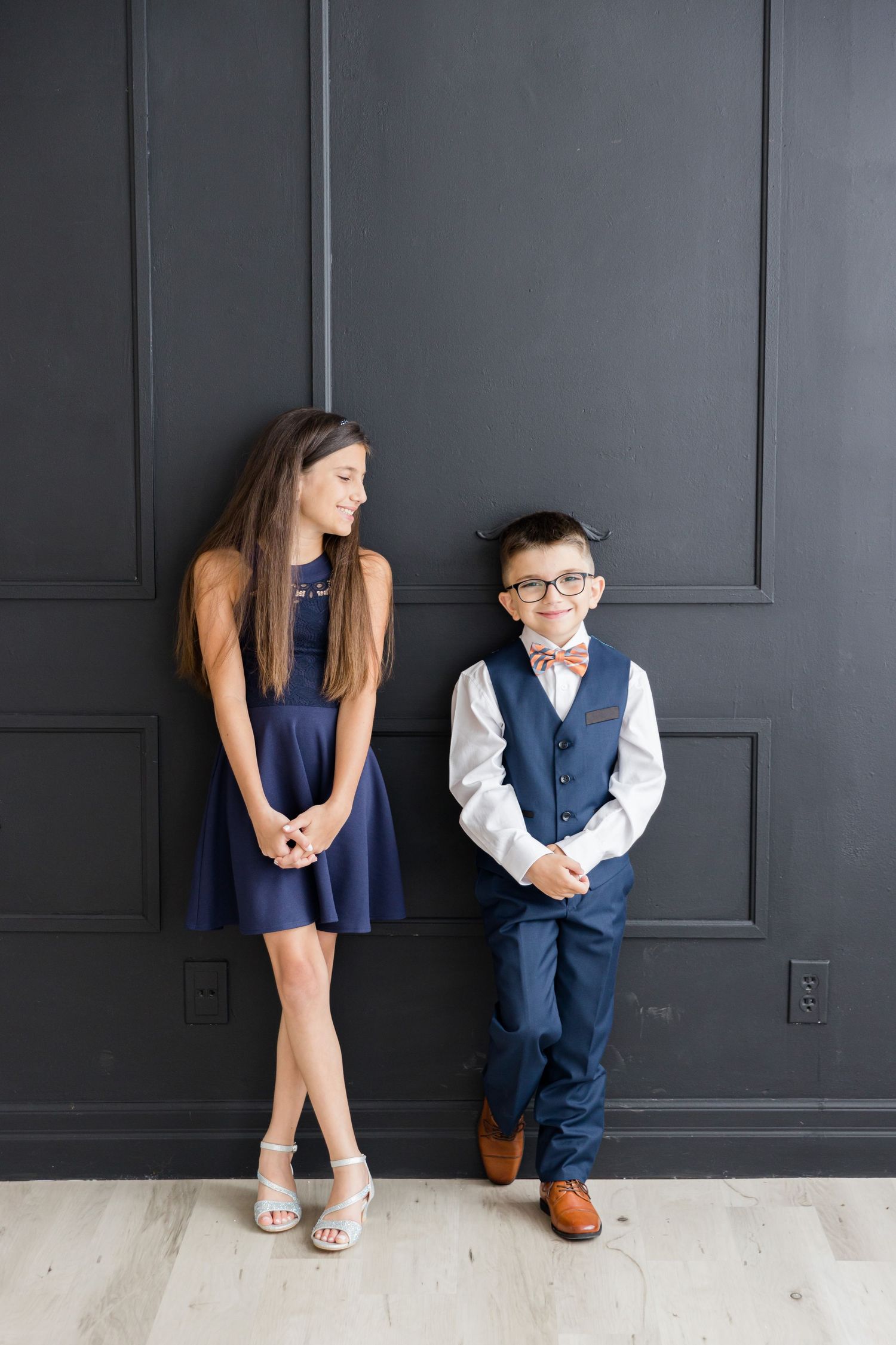 Elegant navy and white coordinated outfits posed against a dark gray wall.