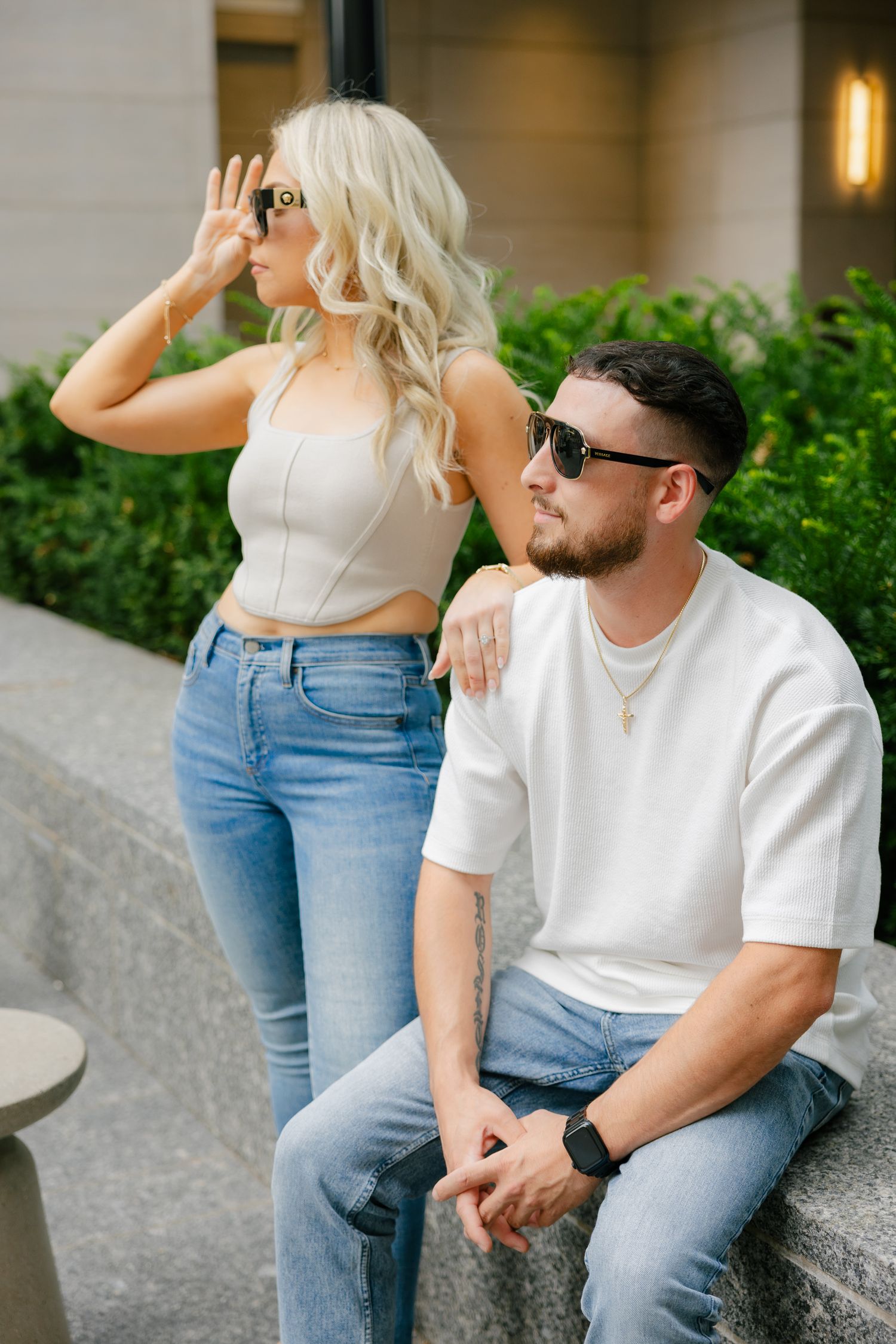 Urban fashion portrait of couple wearing sunglasses by modern building.