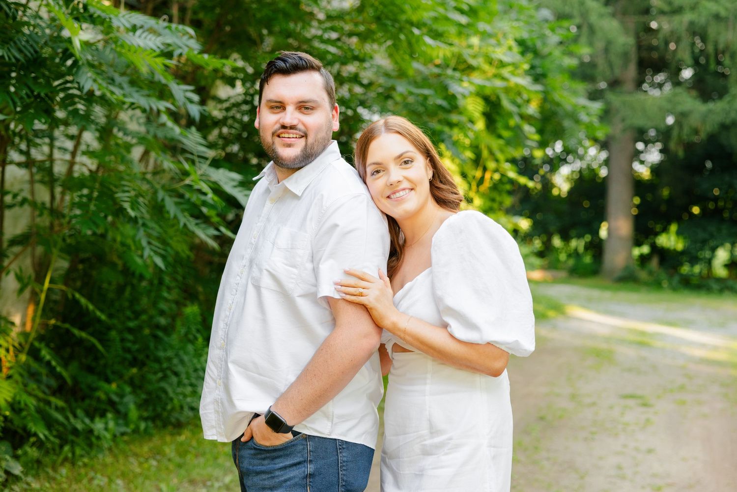 A couple shares a joyful moment together in front of a weathered barn on a summer day.