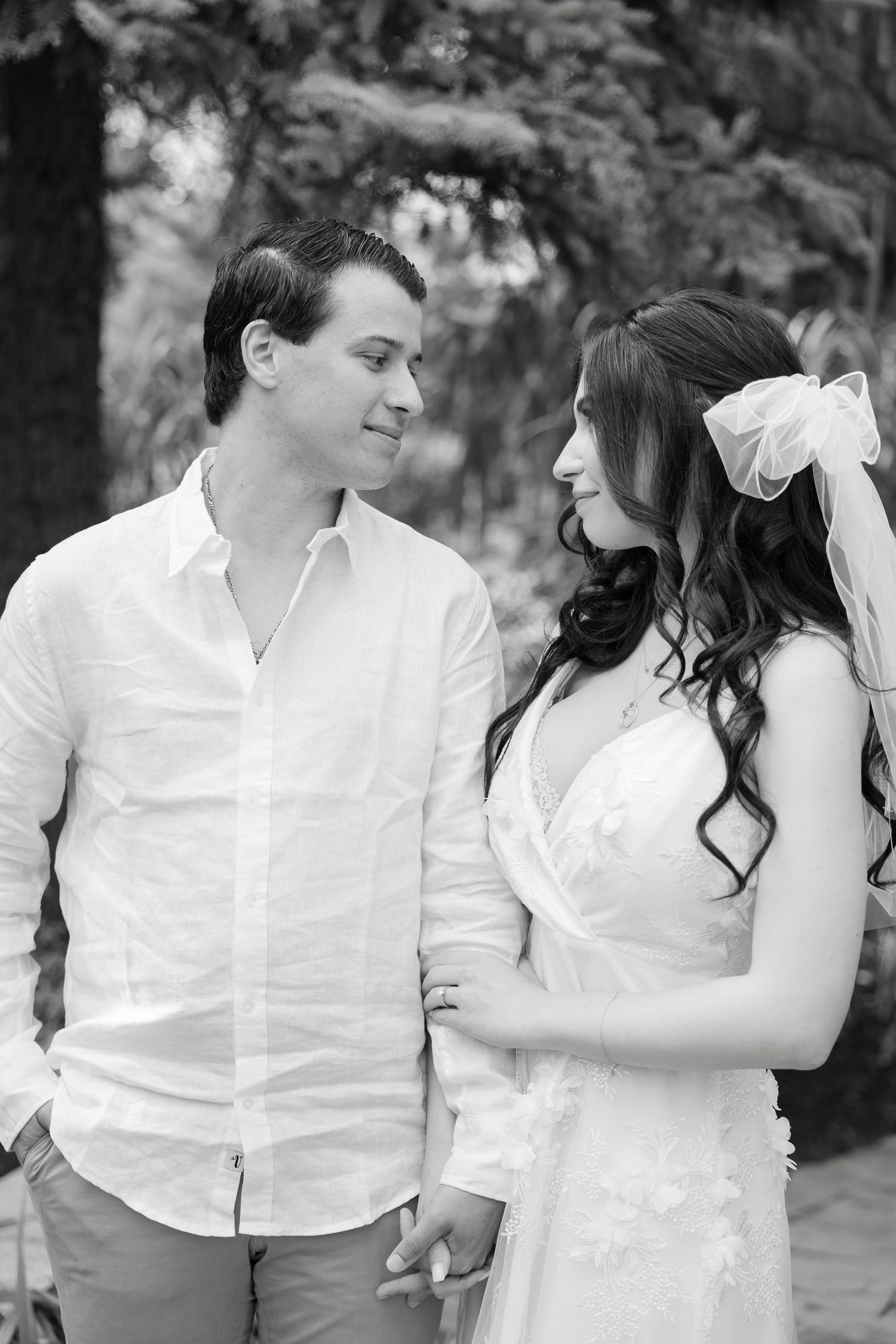 A black and white wedding photo showing a couple sharing an intimate moment in a garden setting.