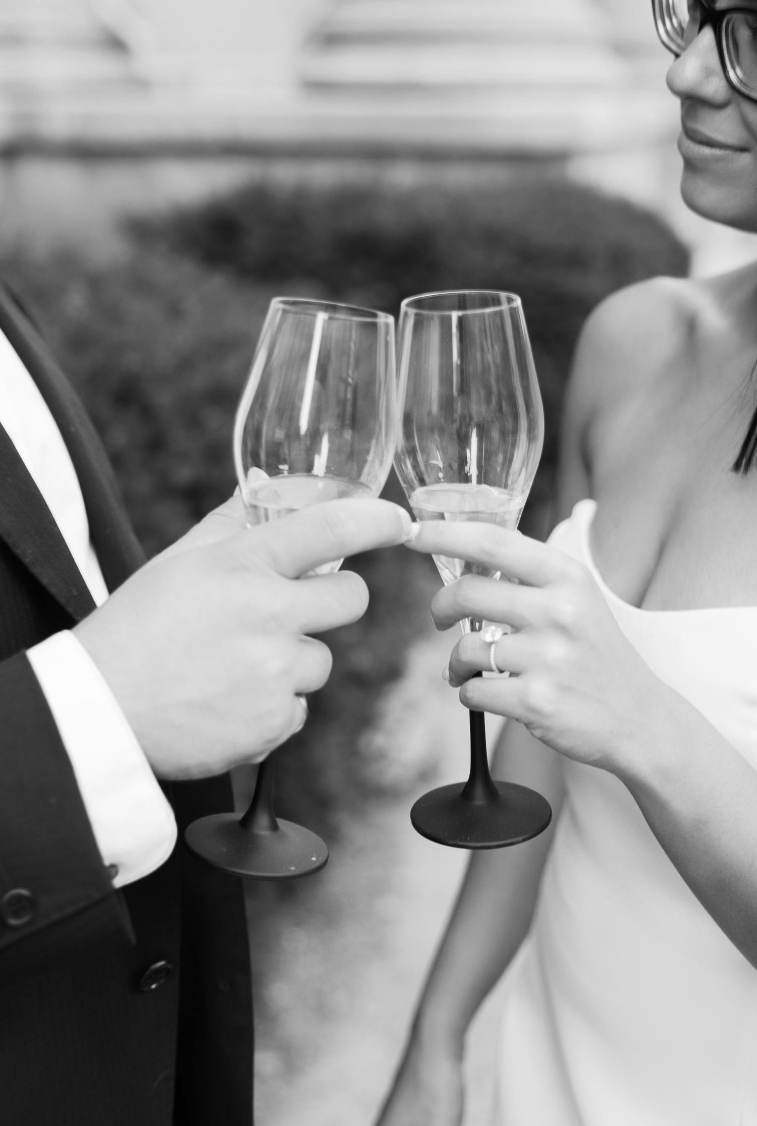 Black and white close-up of hands holding wine glasses during toast.