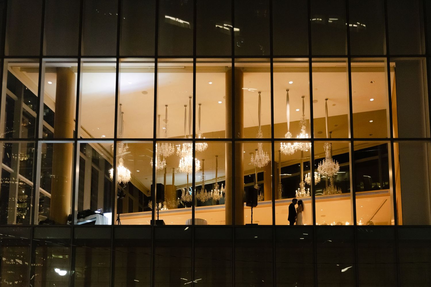 Night view through glass windows of an illuminated modern building interior.