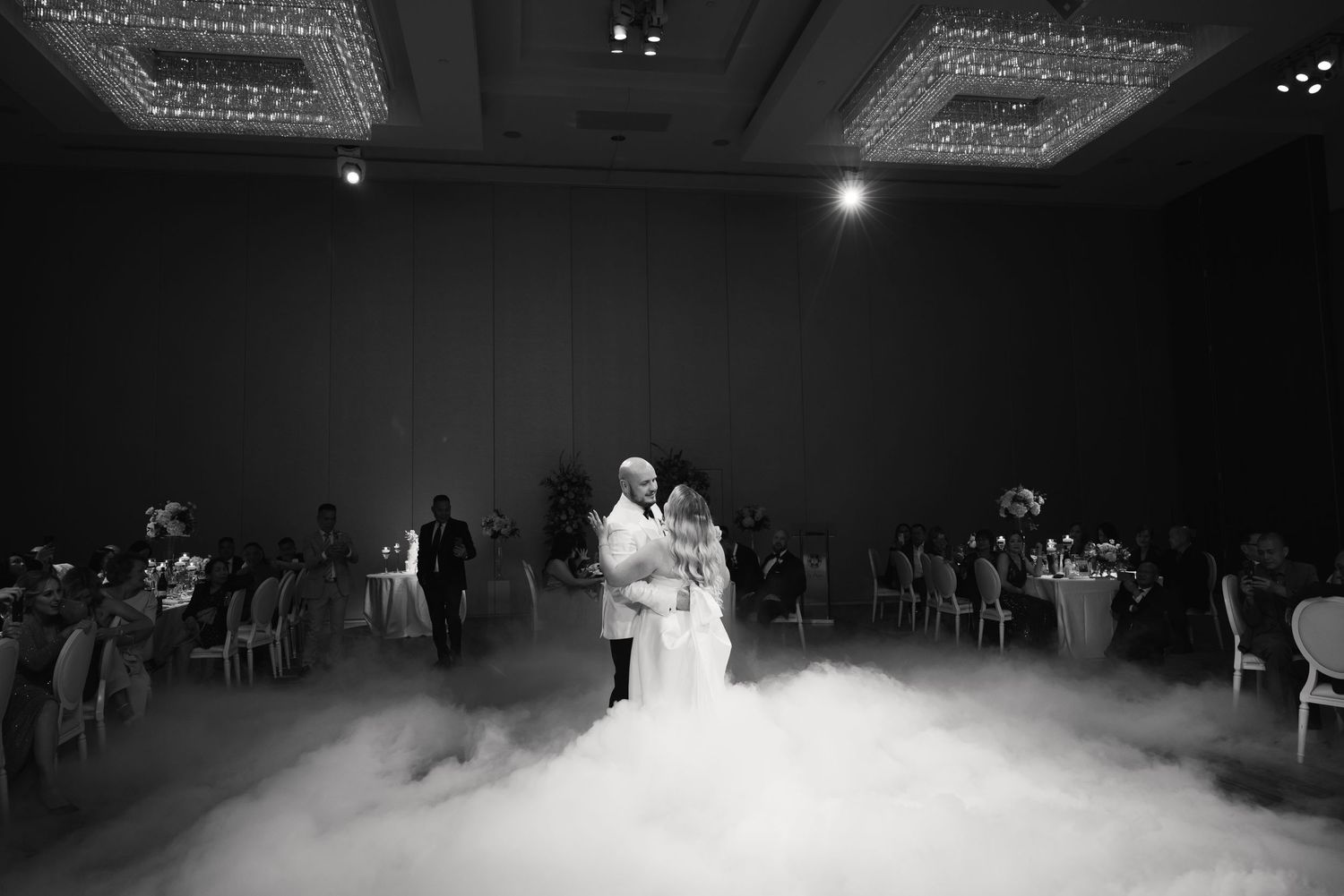 Black and white photo of a romantic first dance with dramatic low-lying fog effects.