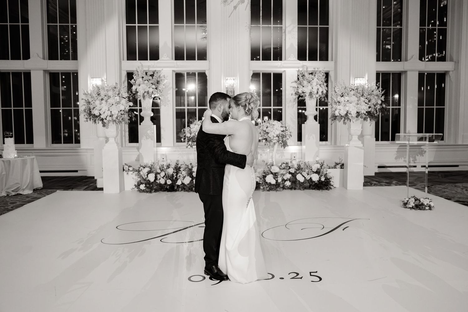 A black and white panoramic collage of wedding moments showing dancing and embracing in an elegant venue with large windows.