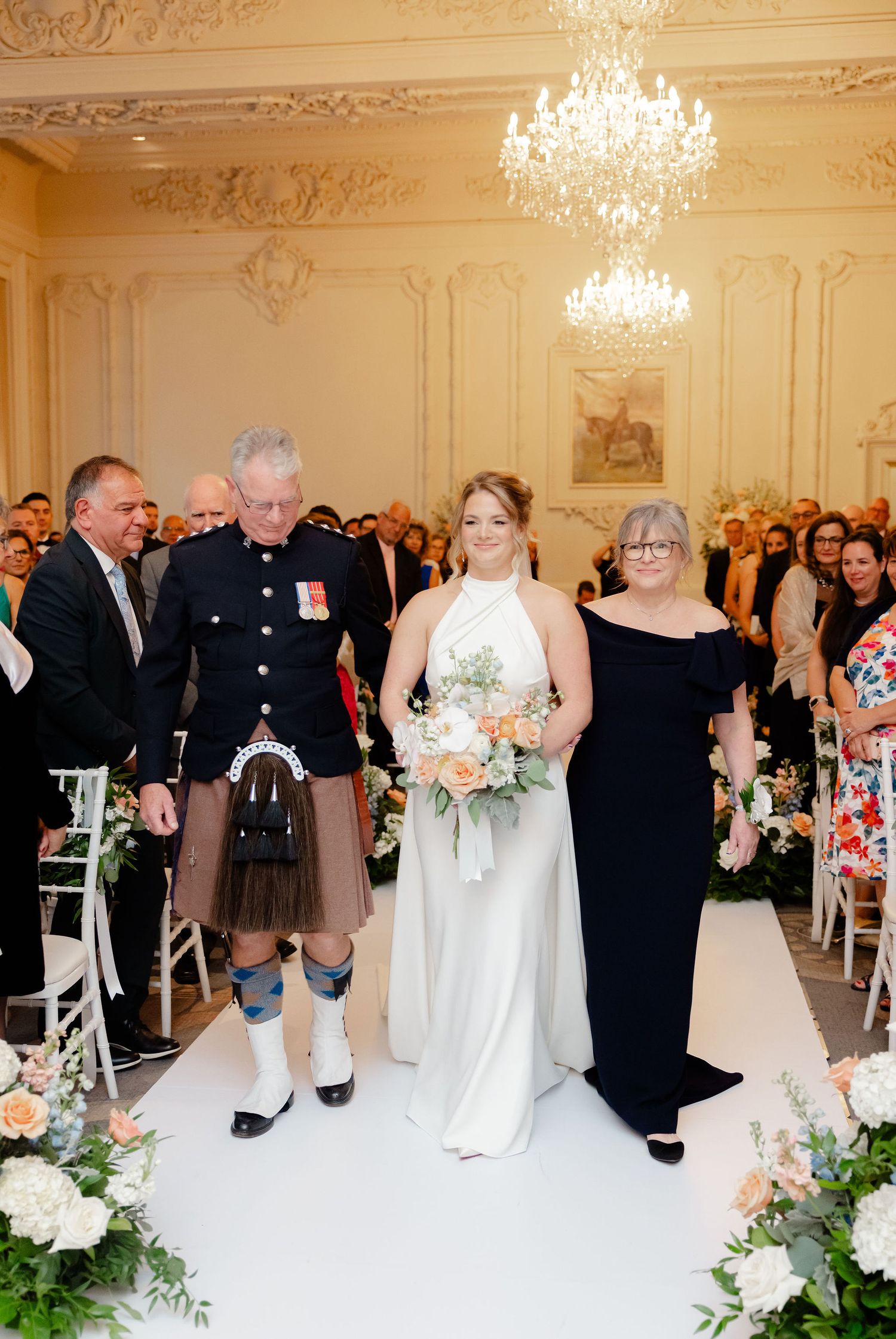 Wedding ceremony setup in elegant ballroom with white aisle runner and floral decorations.