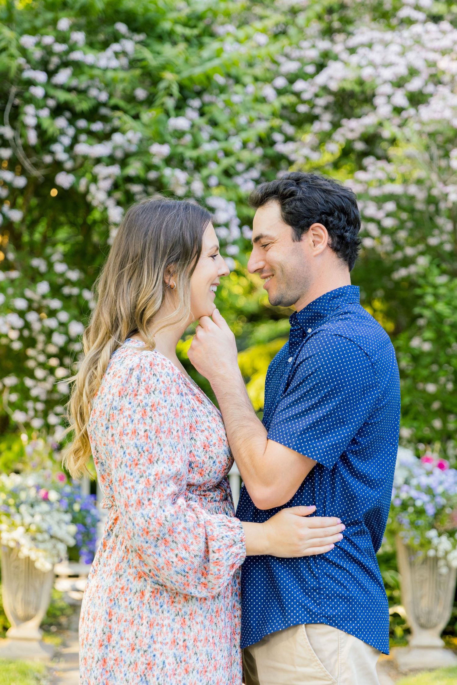 A tender moment captured between a couple in a flowering garden with white blooms.