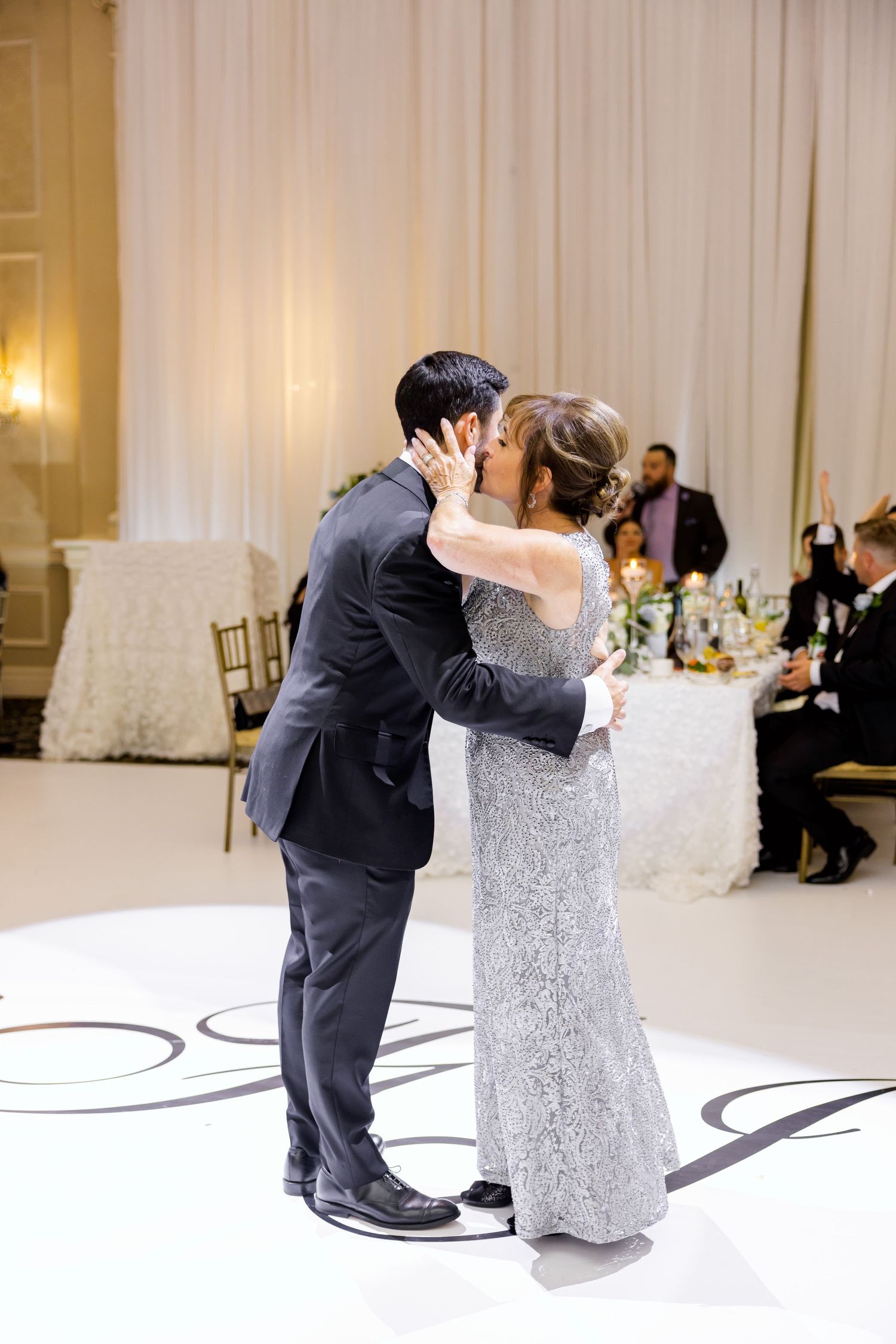 A tender moment captured during a wedding dance on a decorated white dance floor.