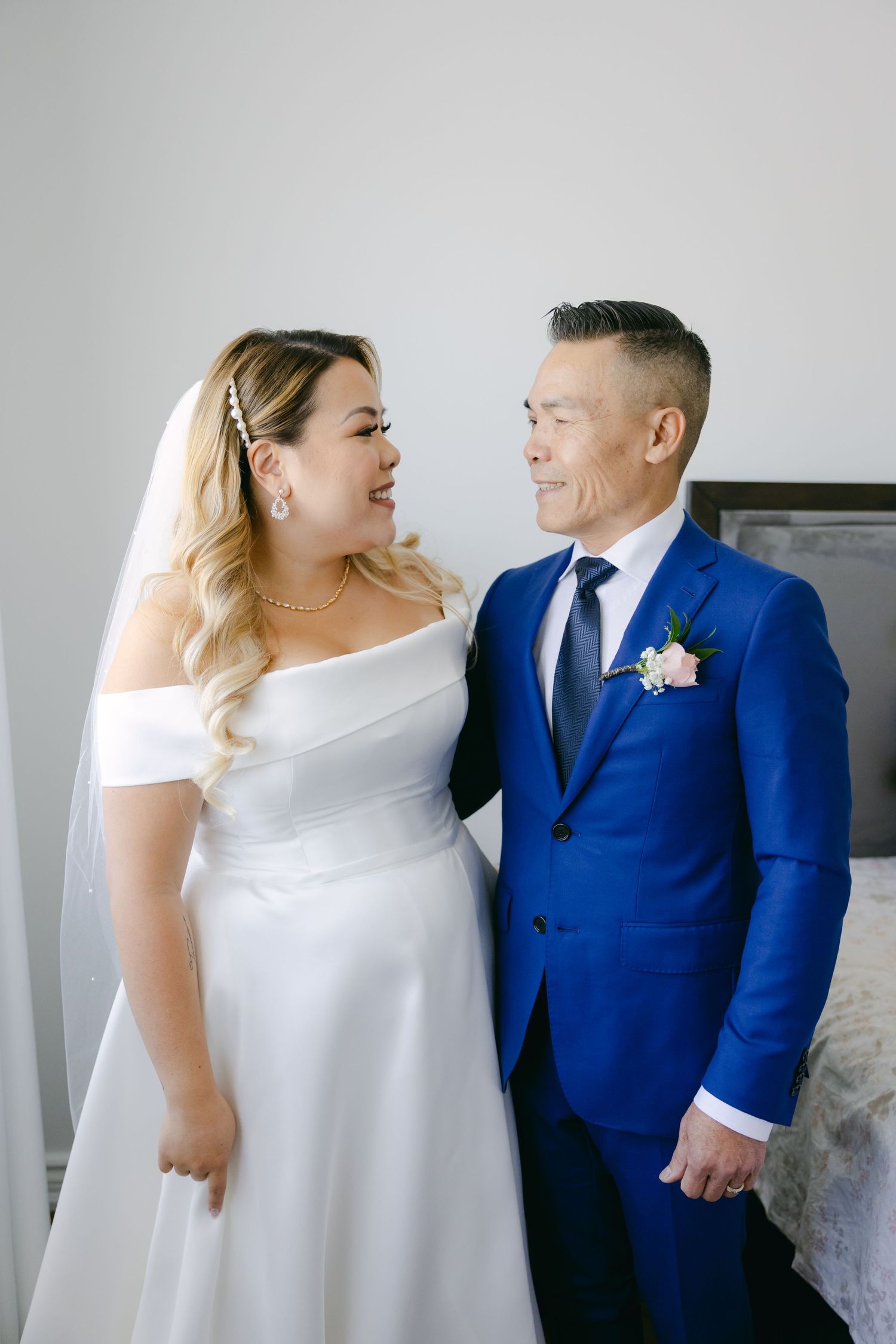 Candid moment of newlyweds laughing together against light background.