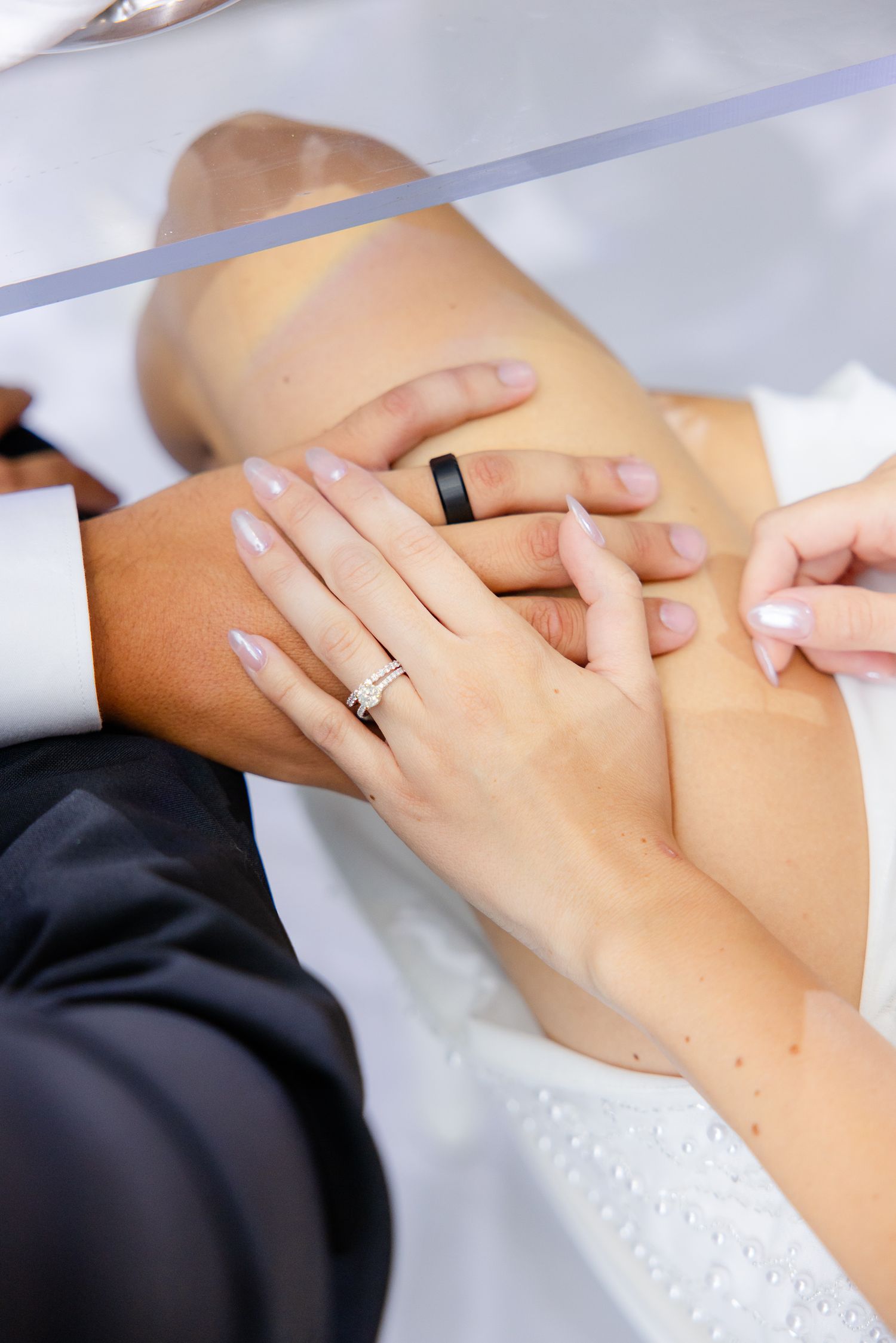 Close-up of hands displaying wedding rings with manicured nails.
