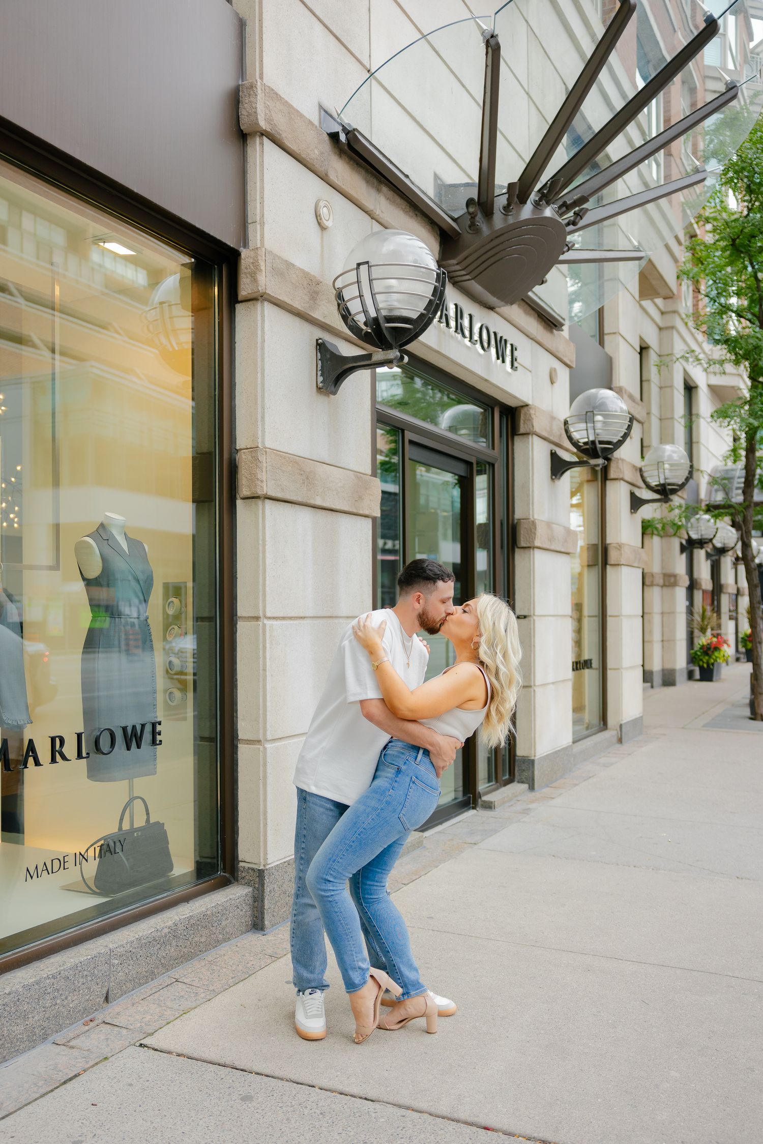 A romantic couple sharing a playful moment outside the Marlowe store.