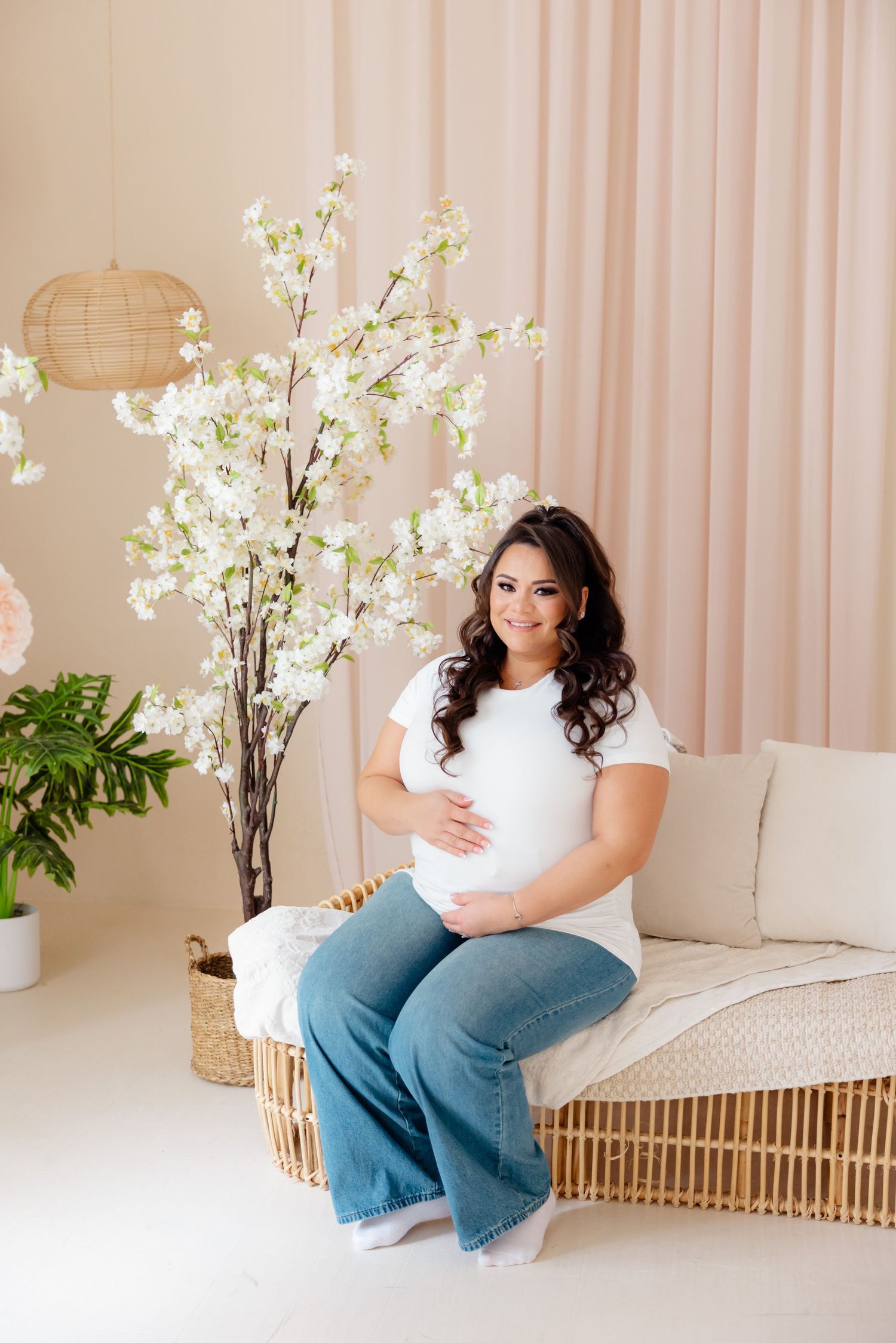 Cozy maternity scene with white blossoms, natural rattan furniture, and neutral decor in a serene indoor setting.