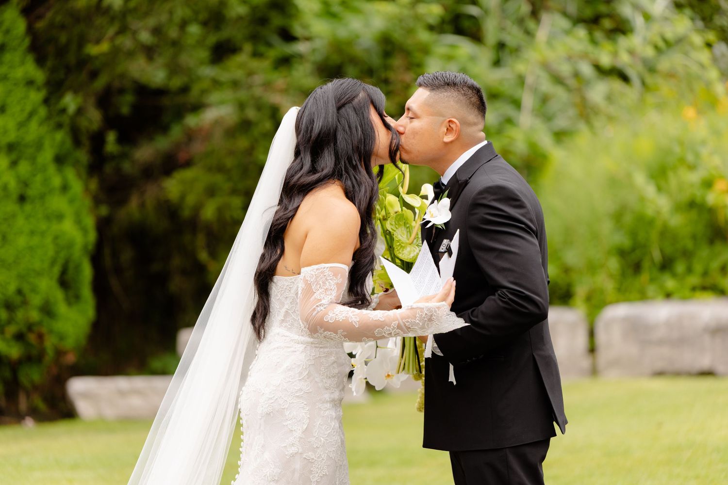 A romantic garden wedding moment as a couple shares tender interactions surrounded by lush greenery.