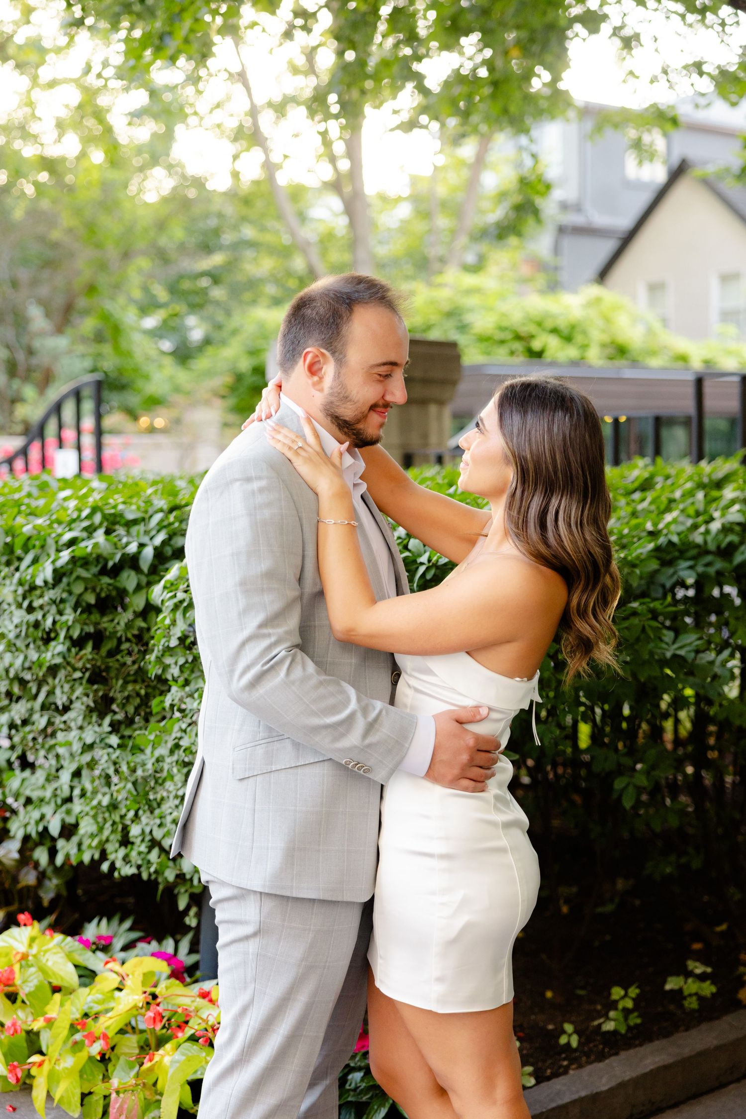 Romantic couple embracing outdoors in front of blooming garden with ornamental fence.
