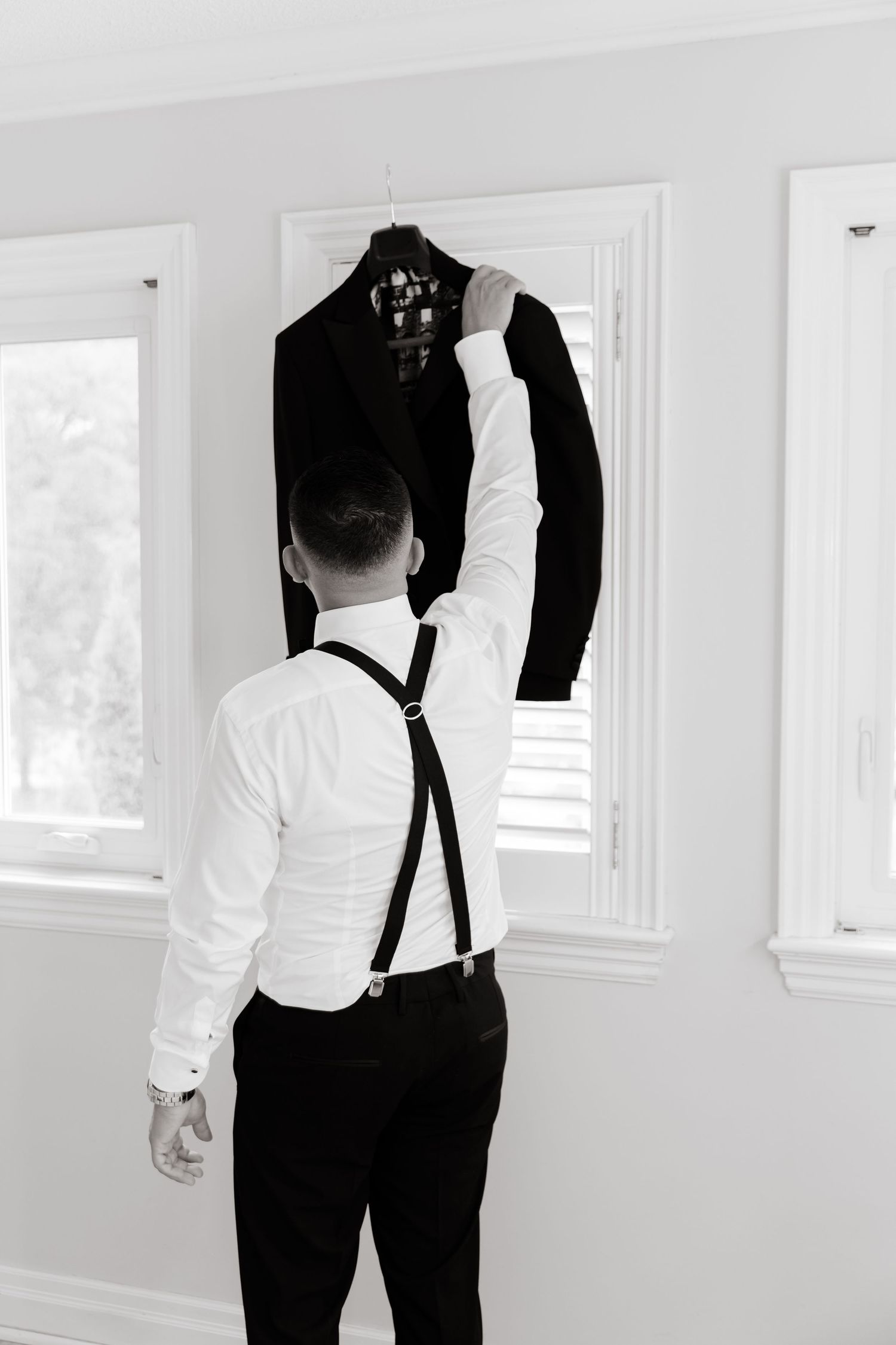 Professional black and white photo series showing details of a formal outfit with suspenders and white dress shirt.