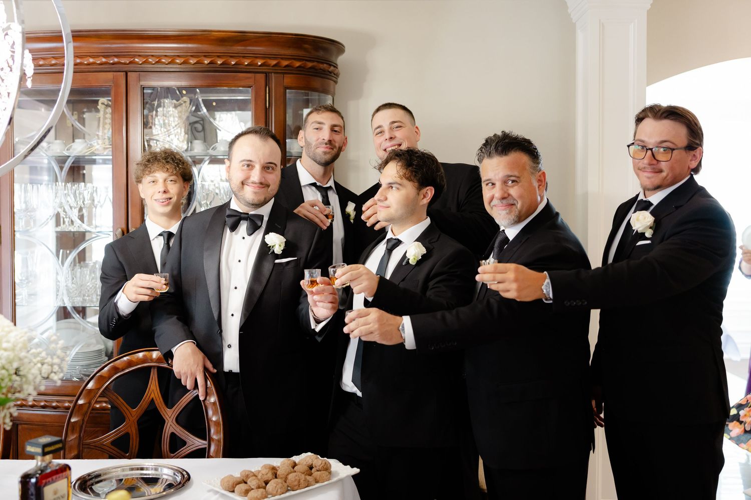Wedding party dressed in formal black and white attire gather for candid moments in multiple group shots.