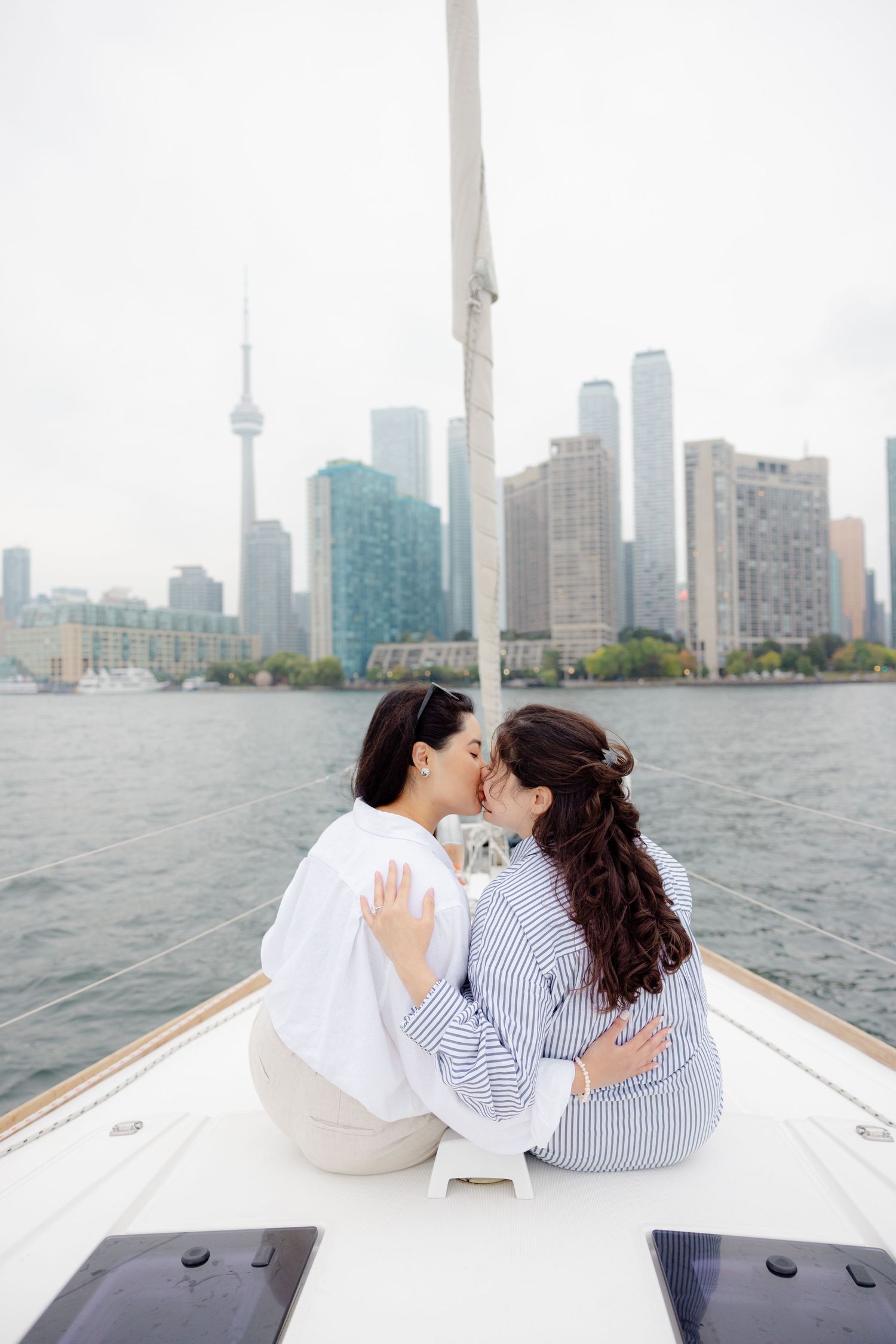 Two people sharing an intimate moment on a boat with Toronto's iconic skyline and CN Tower in the background.