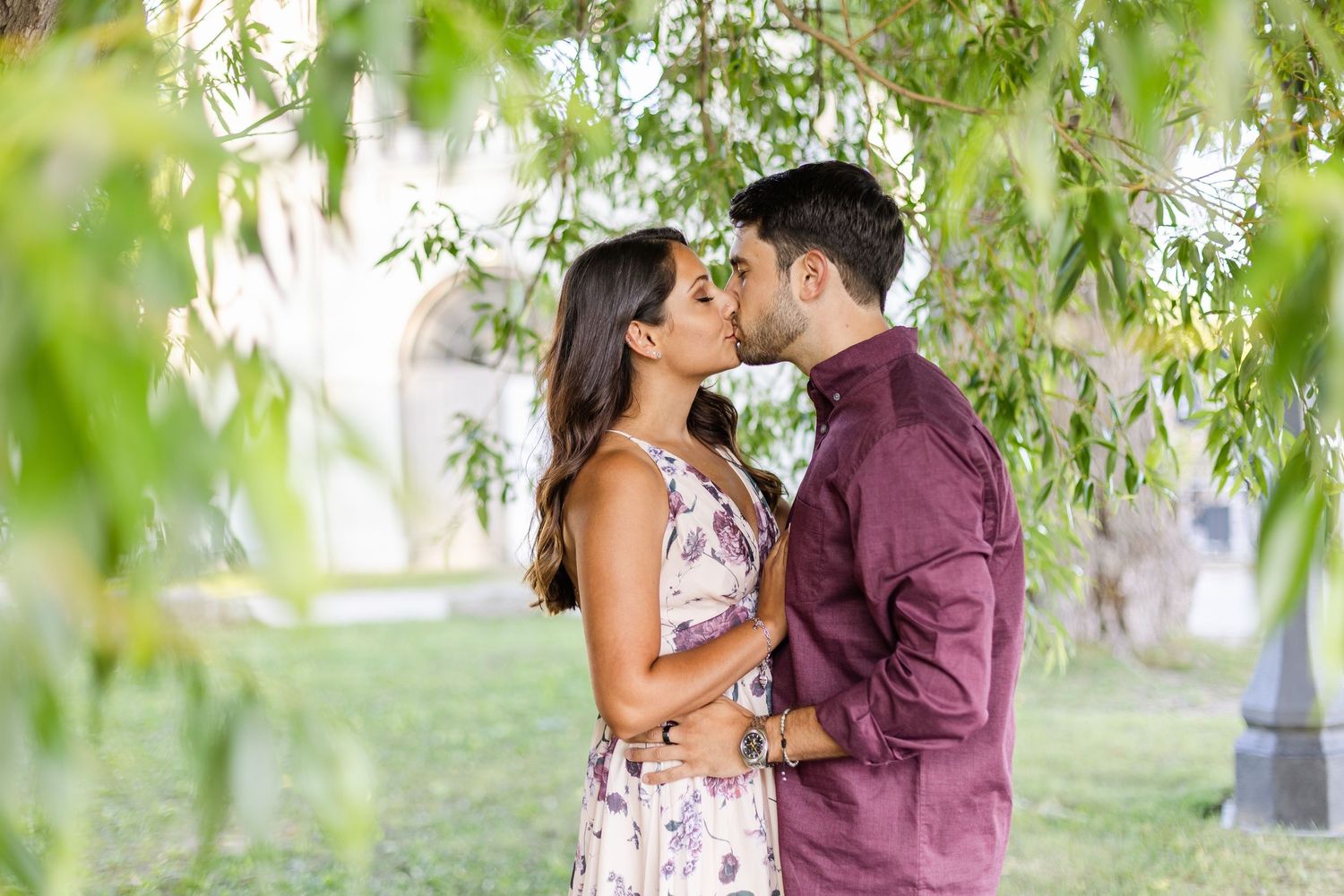 Intimate couple portrait framed by hanging willow branches in an outdoor setting.