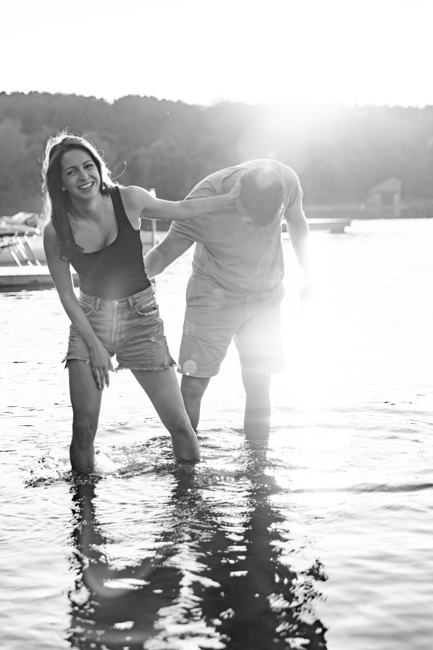 Joyful moment shared between couple playing in lake water during sunset.