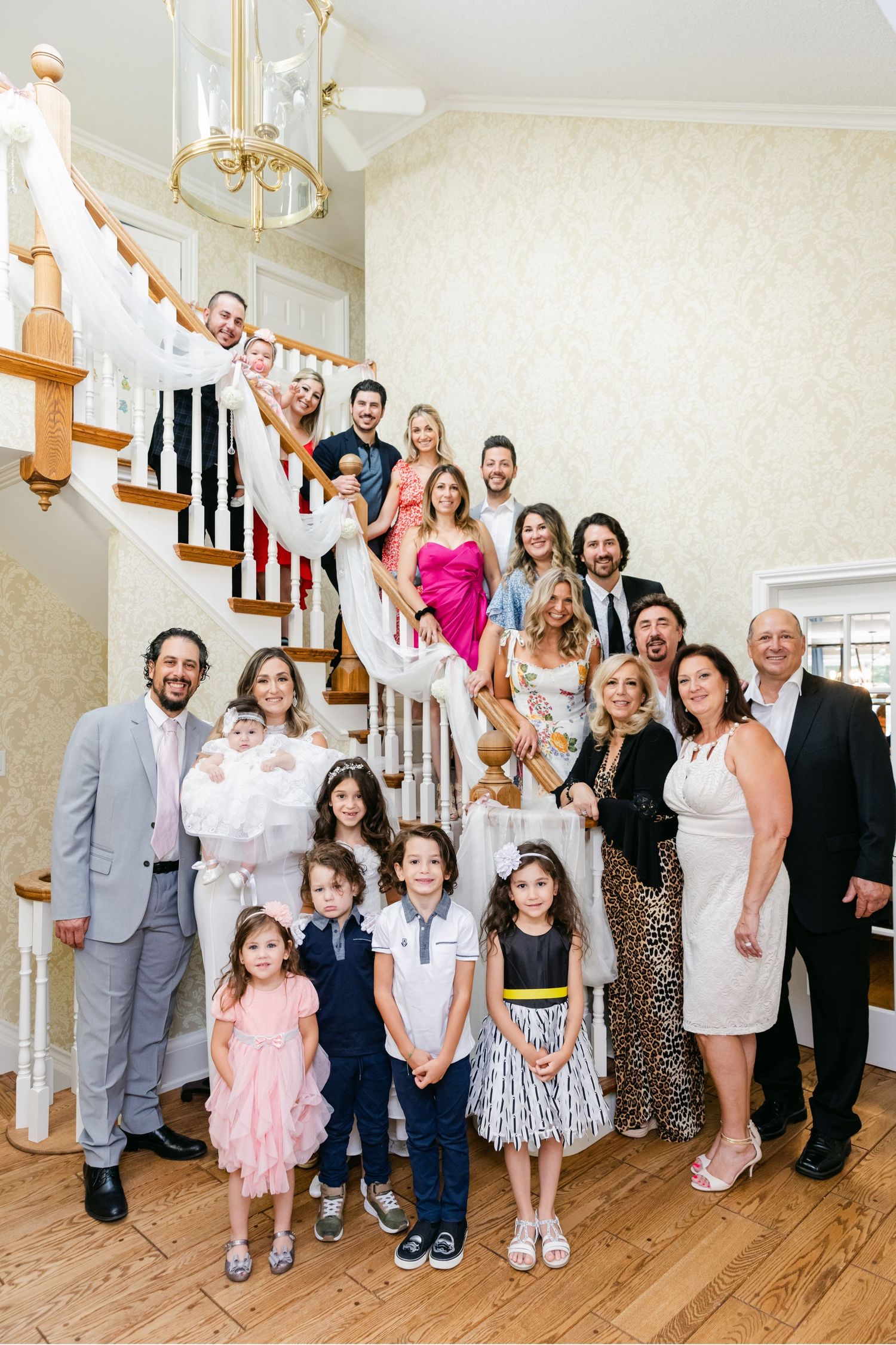 Large family group photo arranged on an elegant white staircase at a formal gathering.
