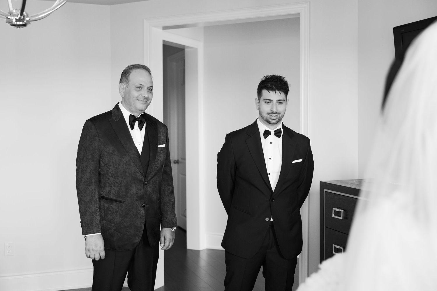 Two suited guests share a moment while waiting in formal attire.