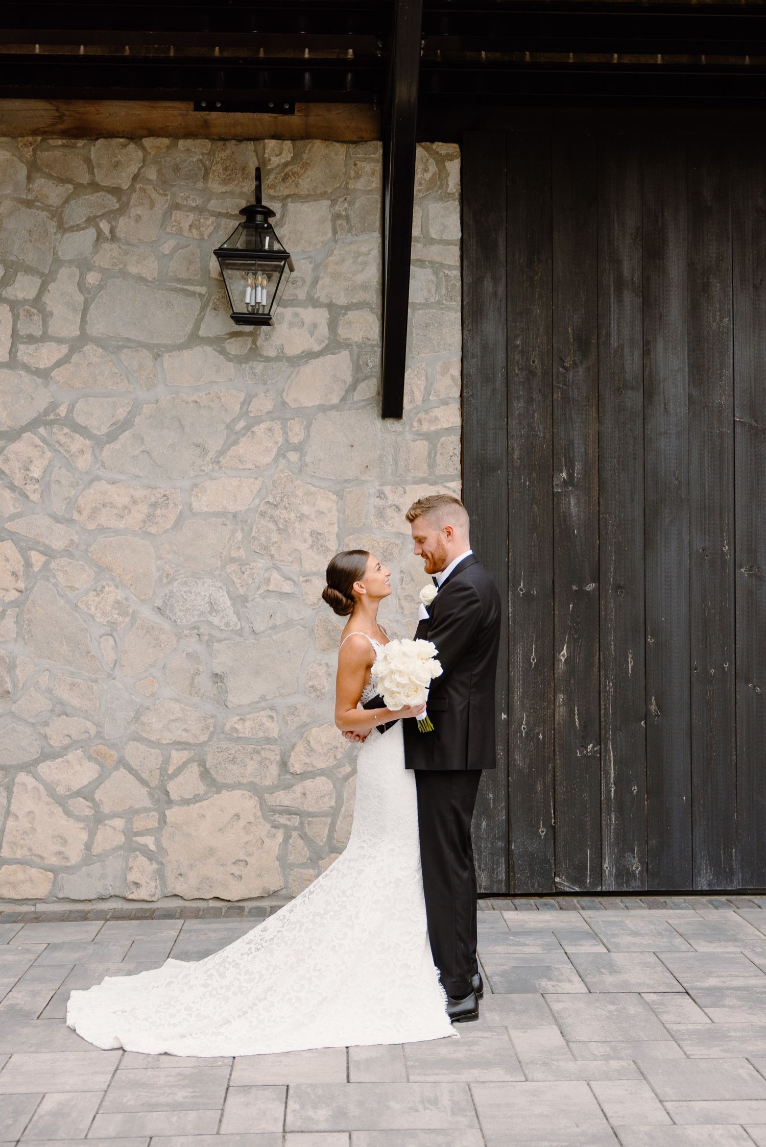 Elegant wedding portrait with stone wall and vintage lantern backdrop.