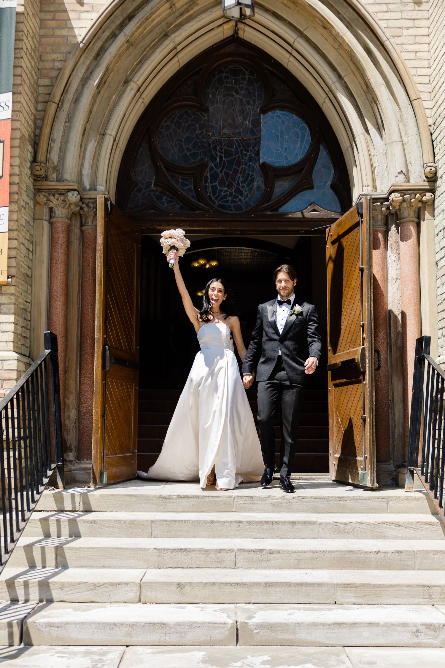 Newlyweds celebrate while exiting historic church steps after their wedding ceremony.