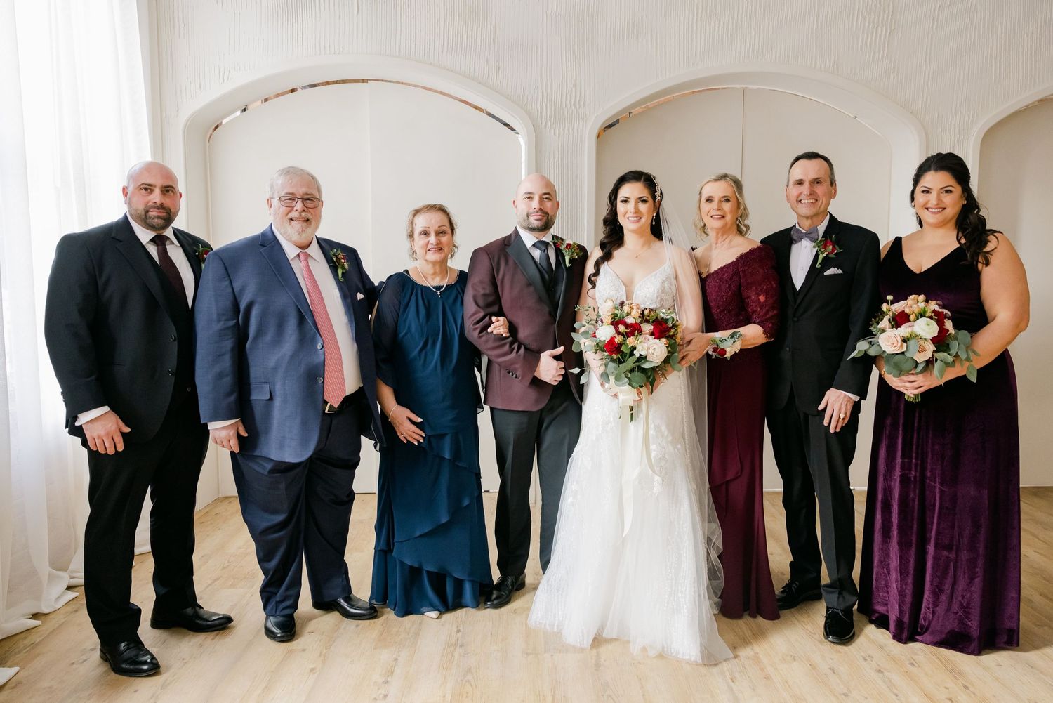 Full wedding party group photo with mixed formal attire in purple and black.