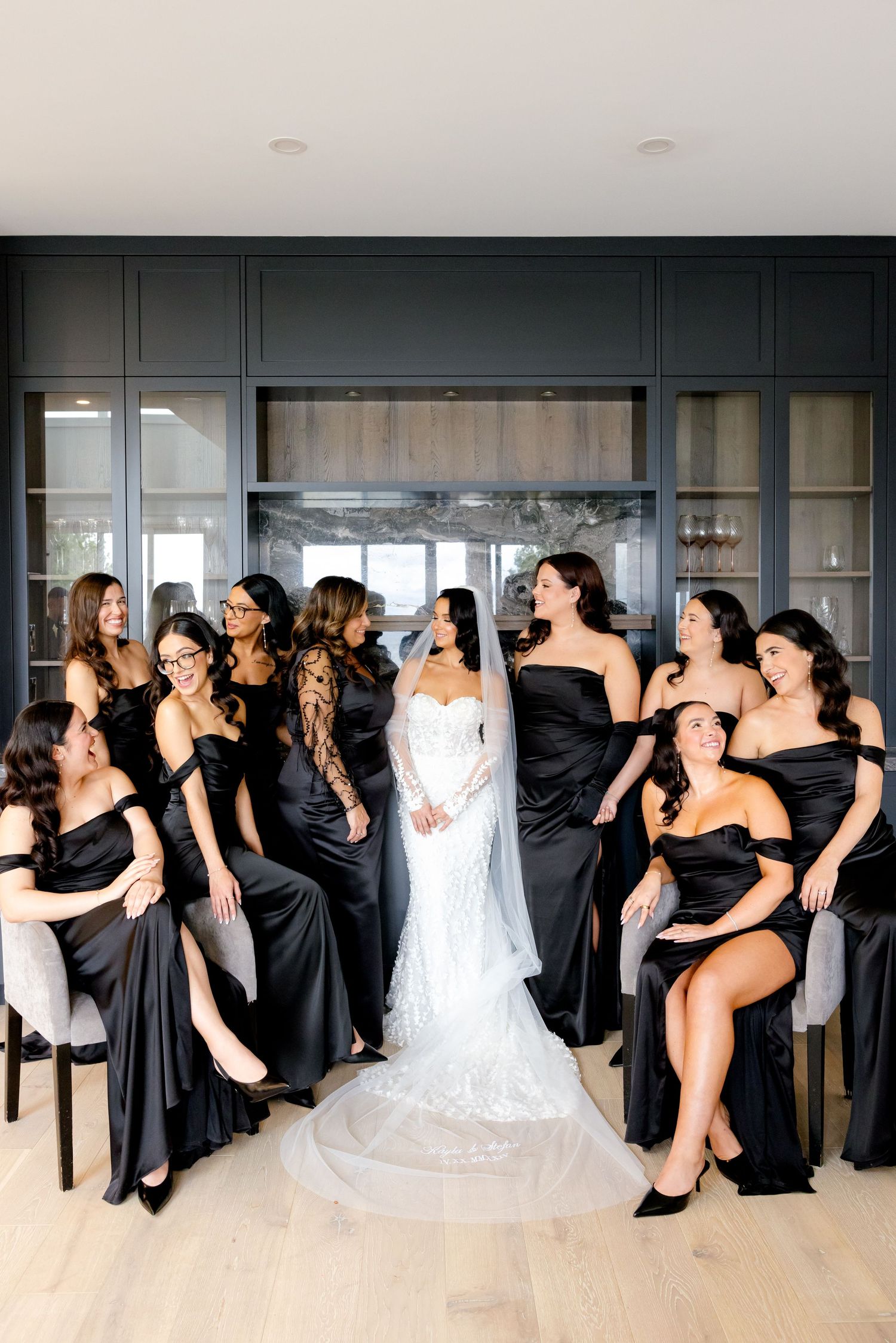 Candid moment of bridal party laughing together in stylish black dresses.