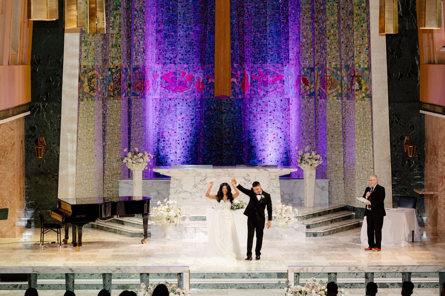 Wide shot of wedding ceremony stage with dramatic purple lighting and musicians performing.