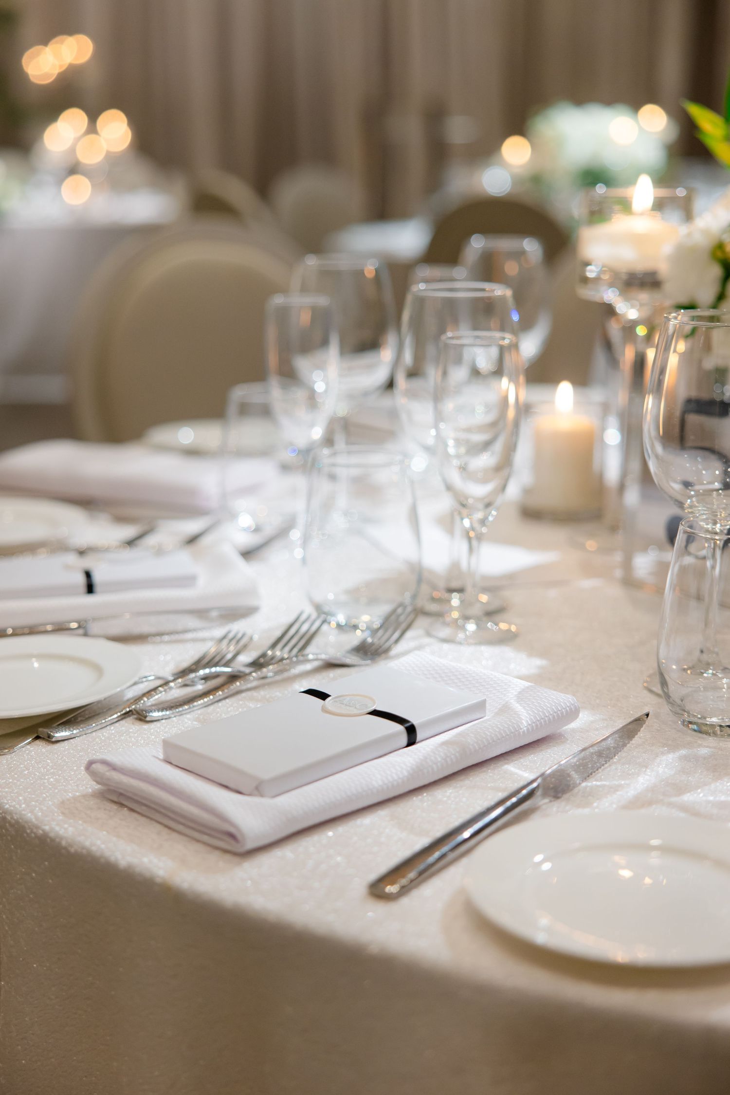 Close-up of formal place setting with white napkin, menu, and wine glasses.