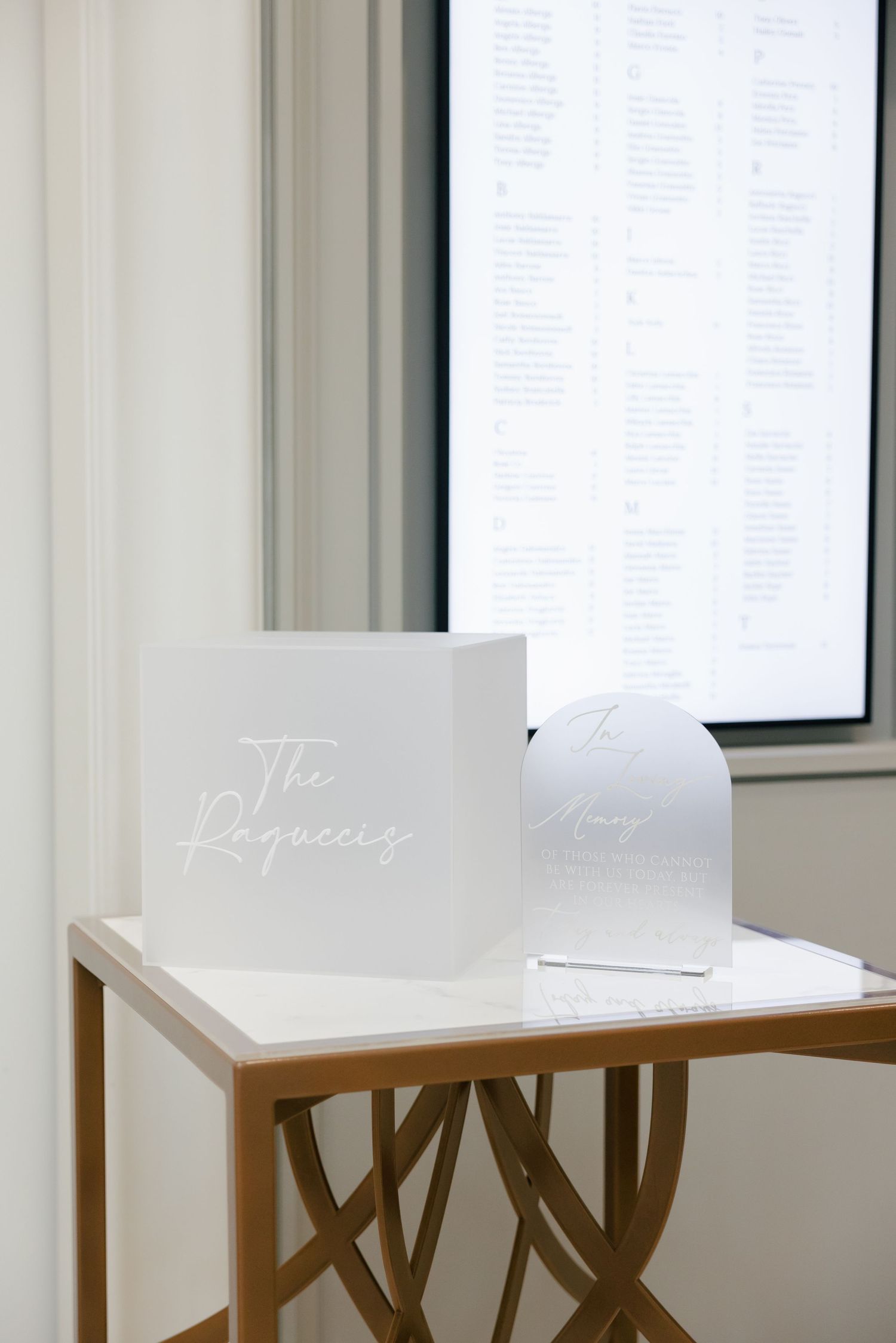 White acrylic signage reading 'The Regency' displayed on wooden stand next to seating chart.