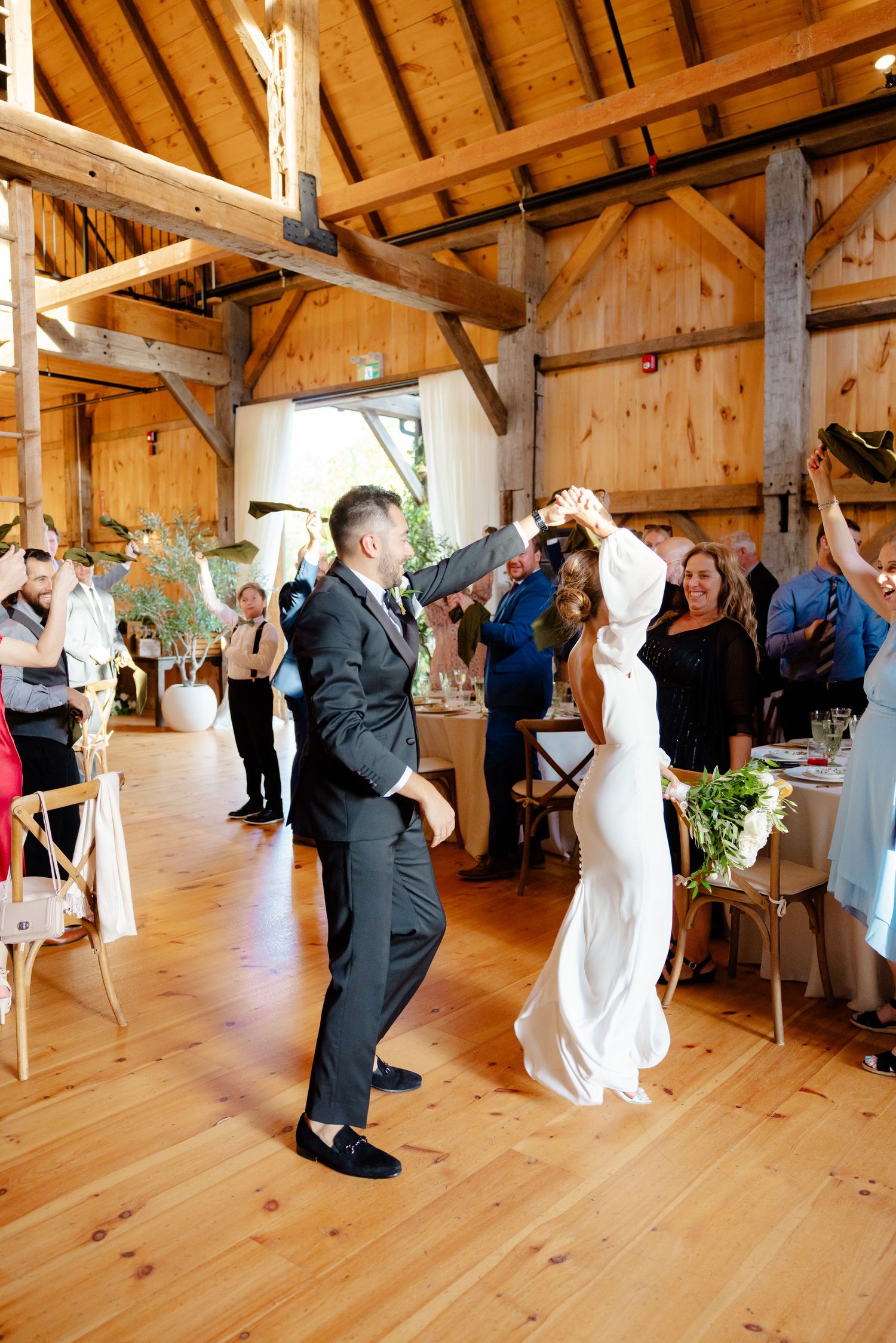 Wedding celebration in a rustic barn venue with wooden beams and joyful dancing.