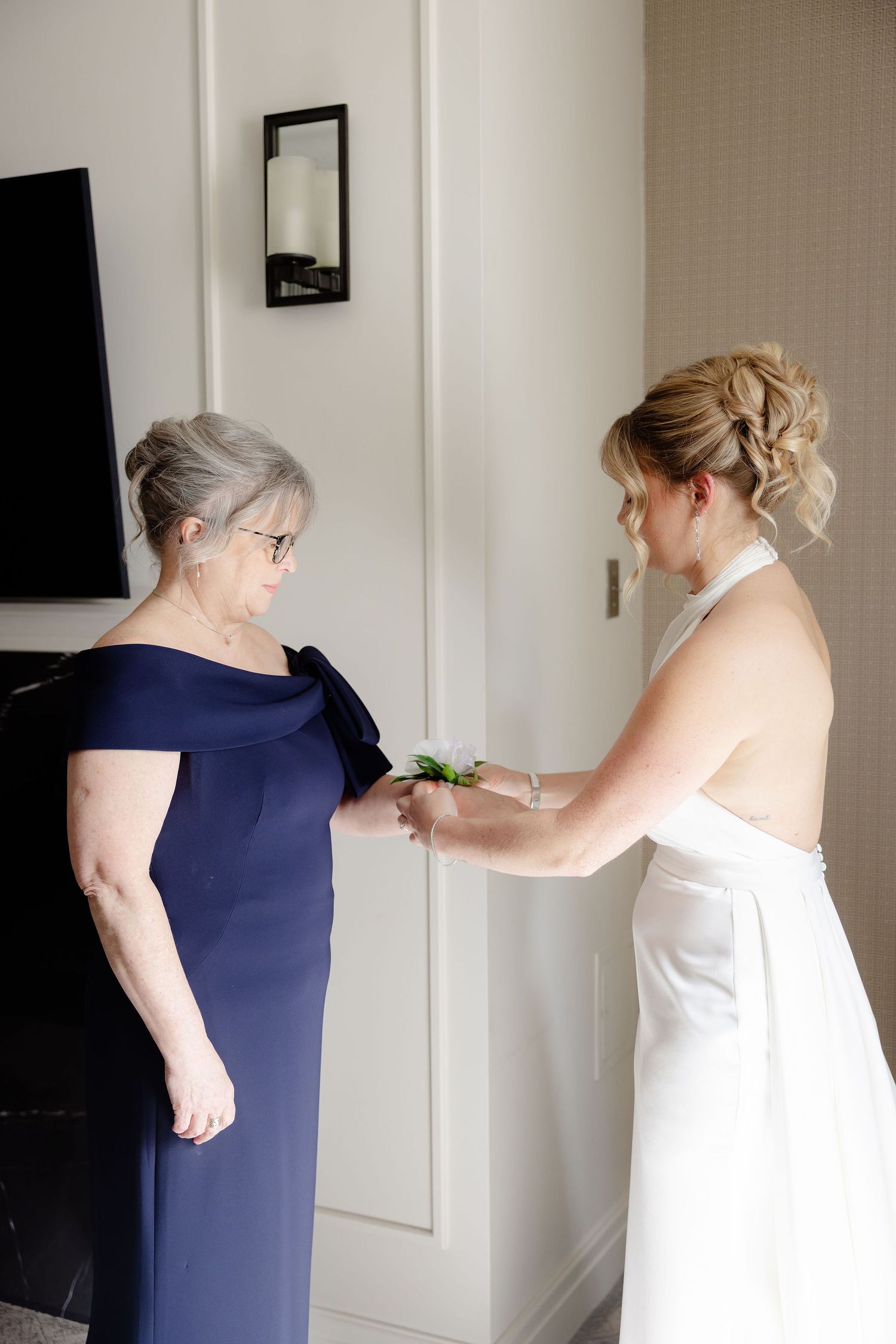 Getting ready scene showing final wedding dress preparations in a sunlit hotel room.