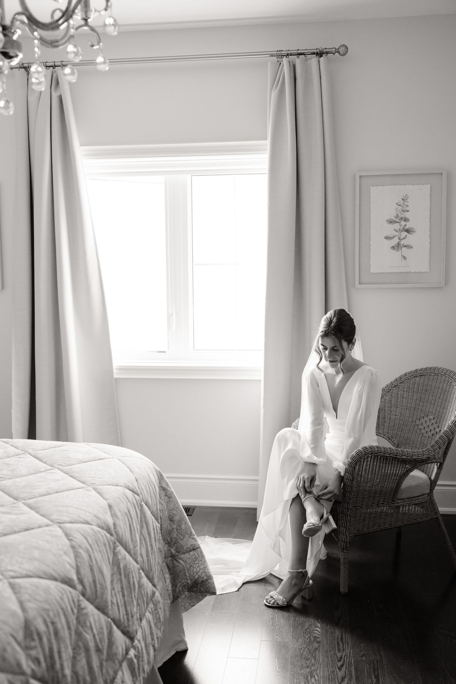 A serene pre-wedding moment in a bright bedroom with wicker chair and elegant curtains.