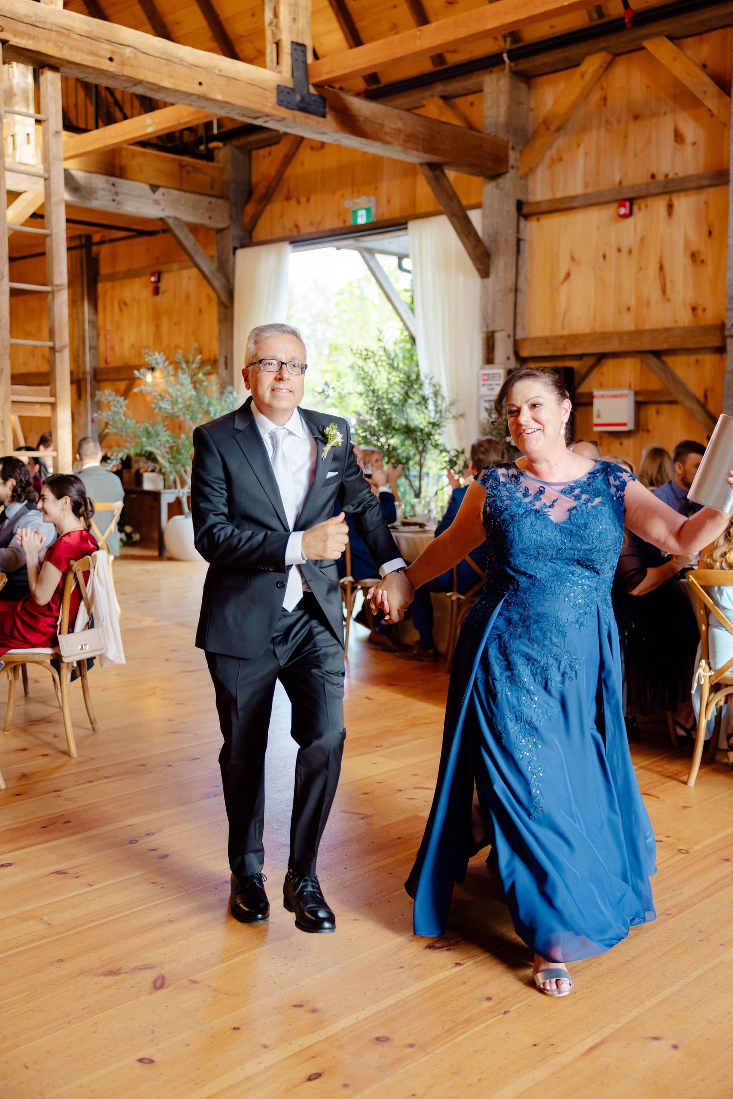 A wedding celebration scene in a rustic barn venue with wooden beams and natural lighting.