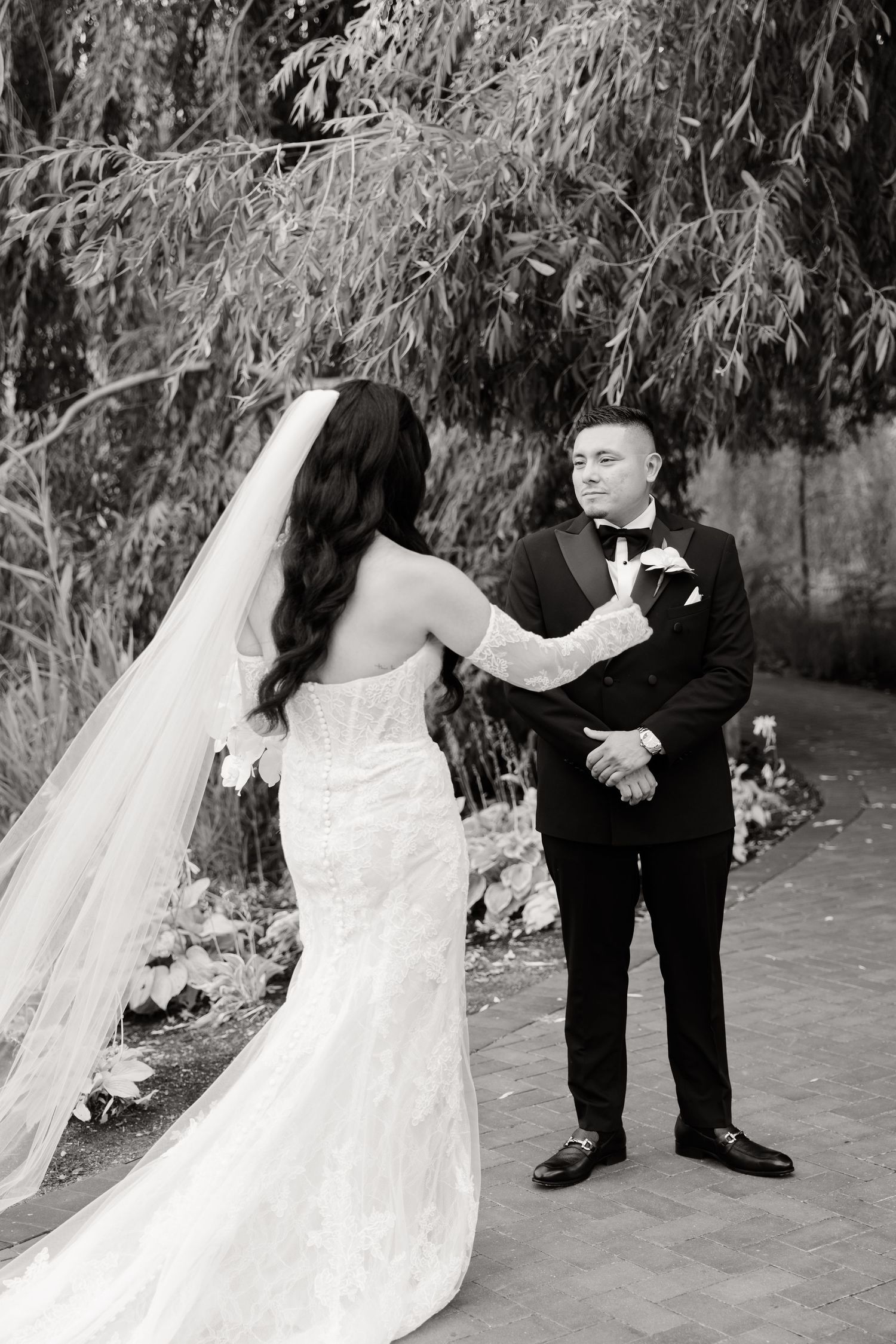 A wedding couple shares a romantic moment under the canopy of a weeping willow tree during their outdoor photoshoot.