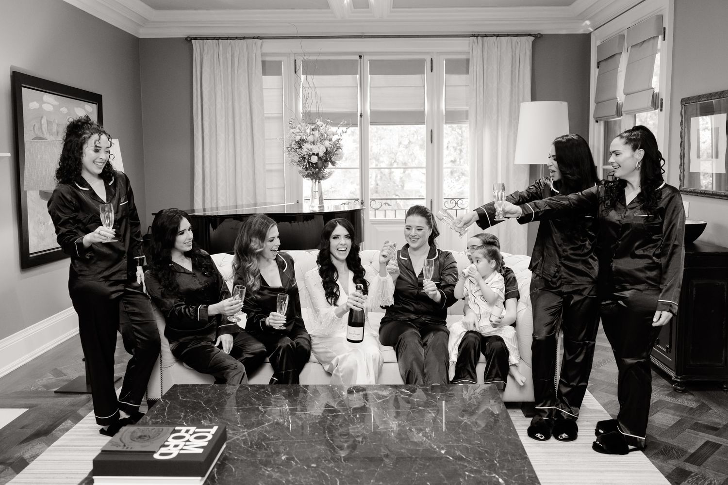Black and white photo of bridal party in matching robes posing together in living room.