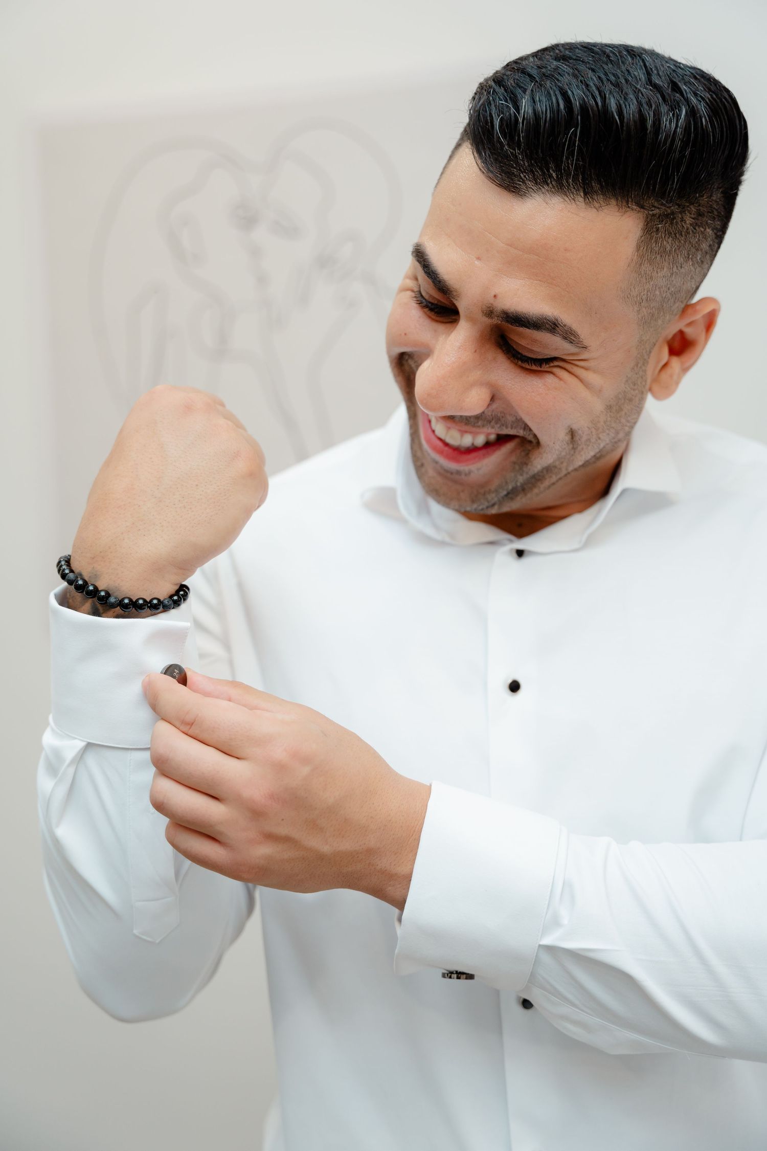 Person in white dress shirt adjusting sleeve with joyful expression.