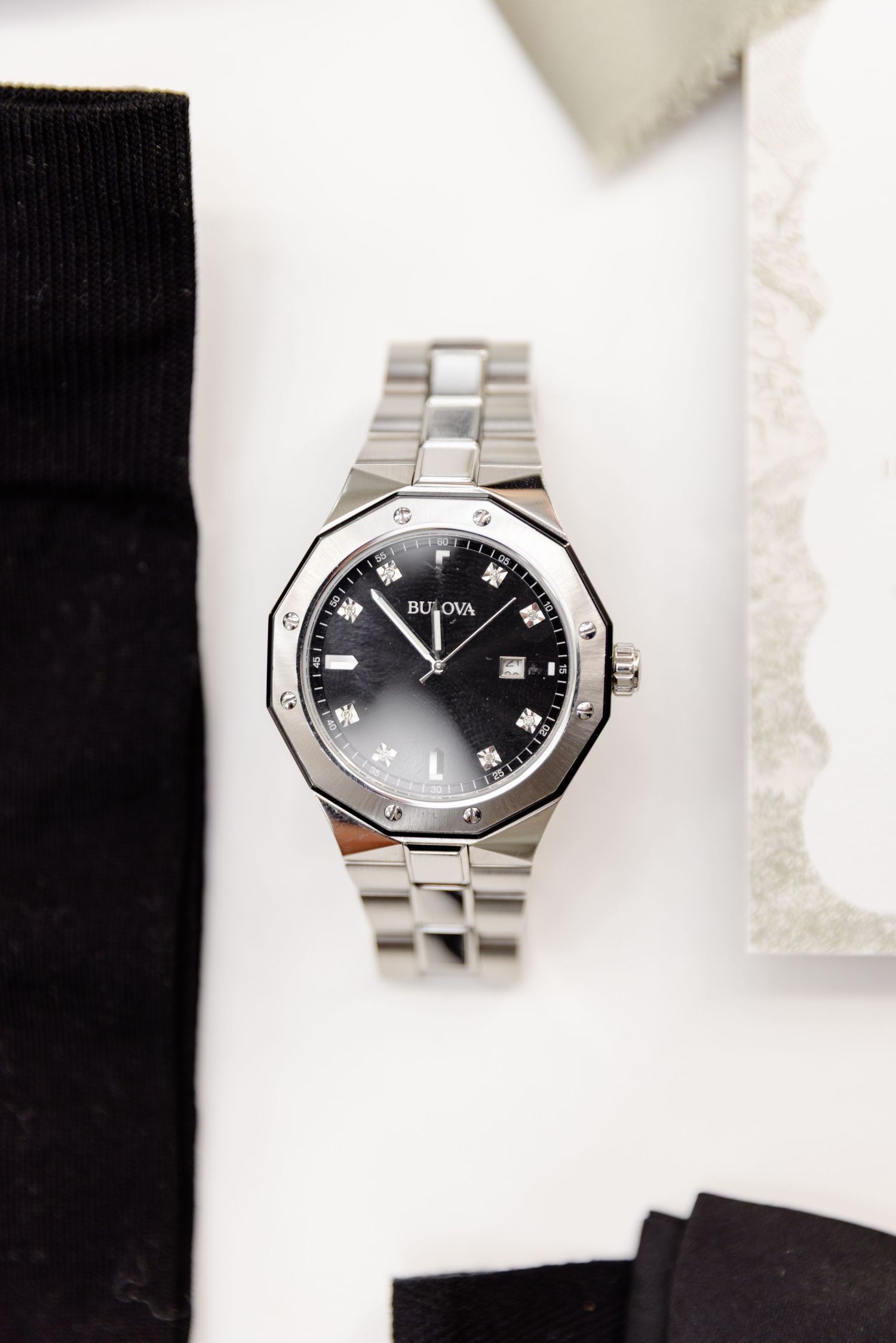 Modern stainless steel Gucci watch with black face and diamond hour markers displayed on white background.