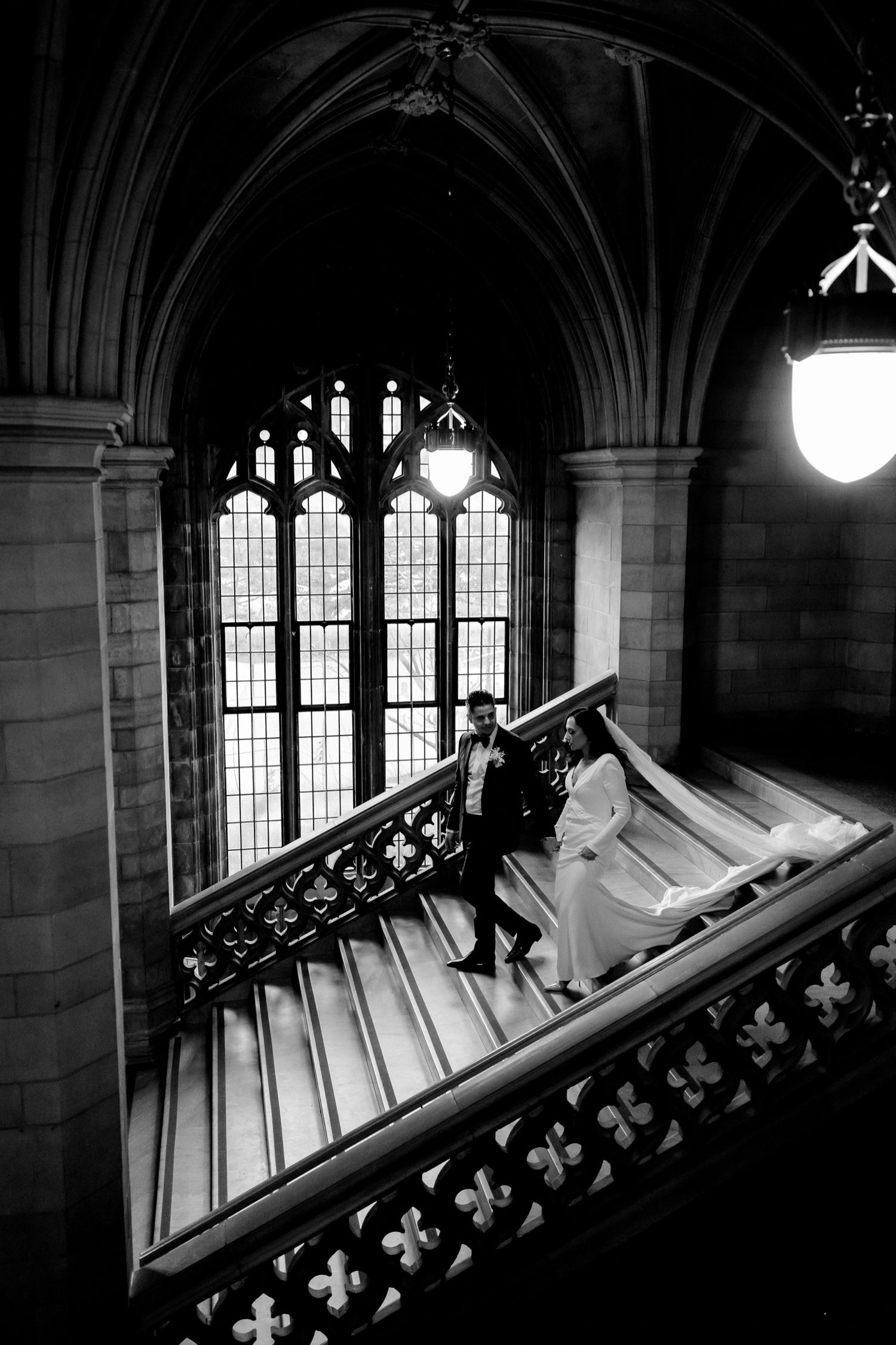 Dramatic black and white wedding photo on a cathedral staircase with gothic architecture.