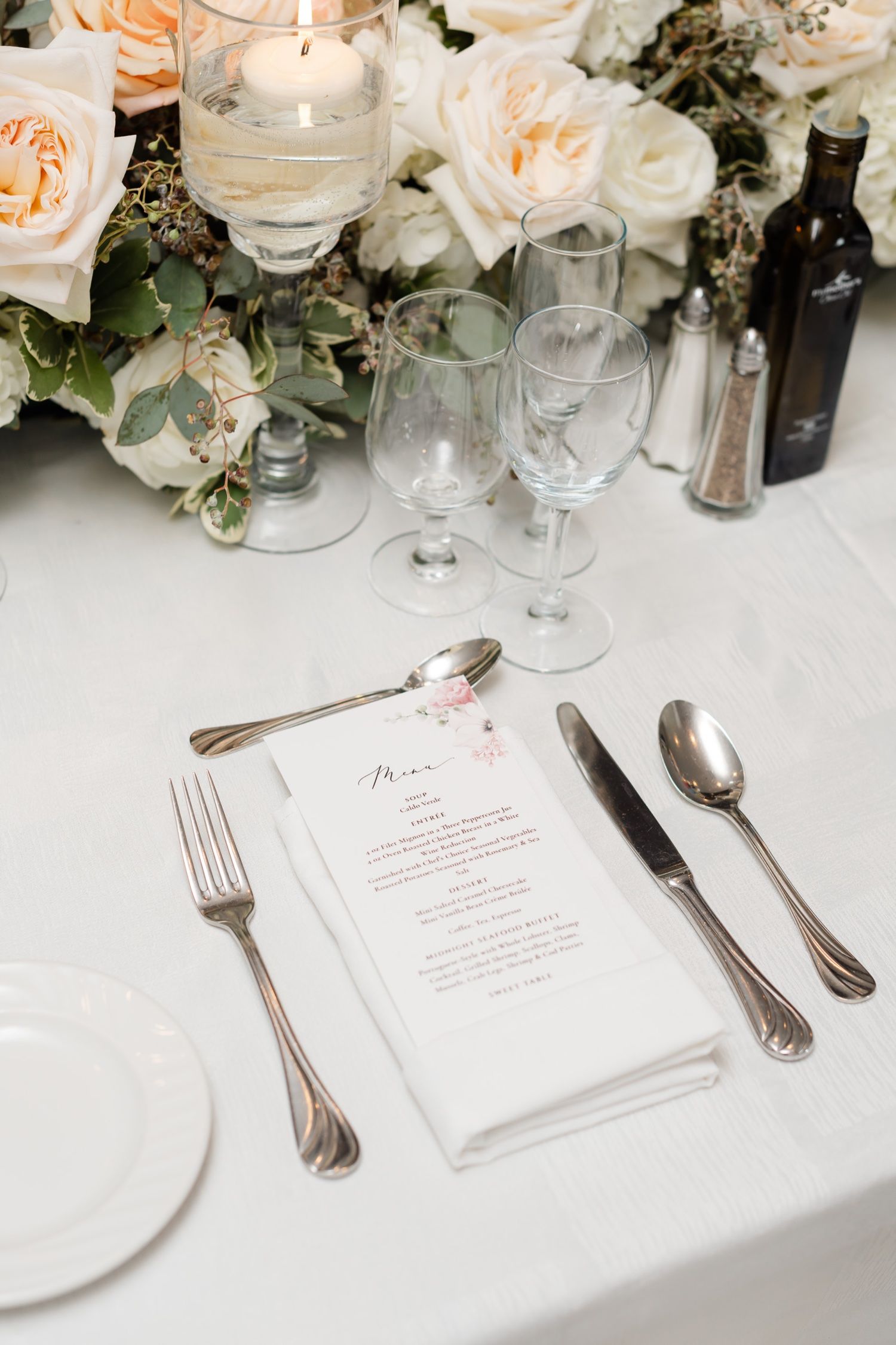 Elegant place setting with menu card, silverware, and peachy rose centerpiece.