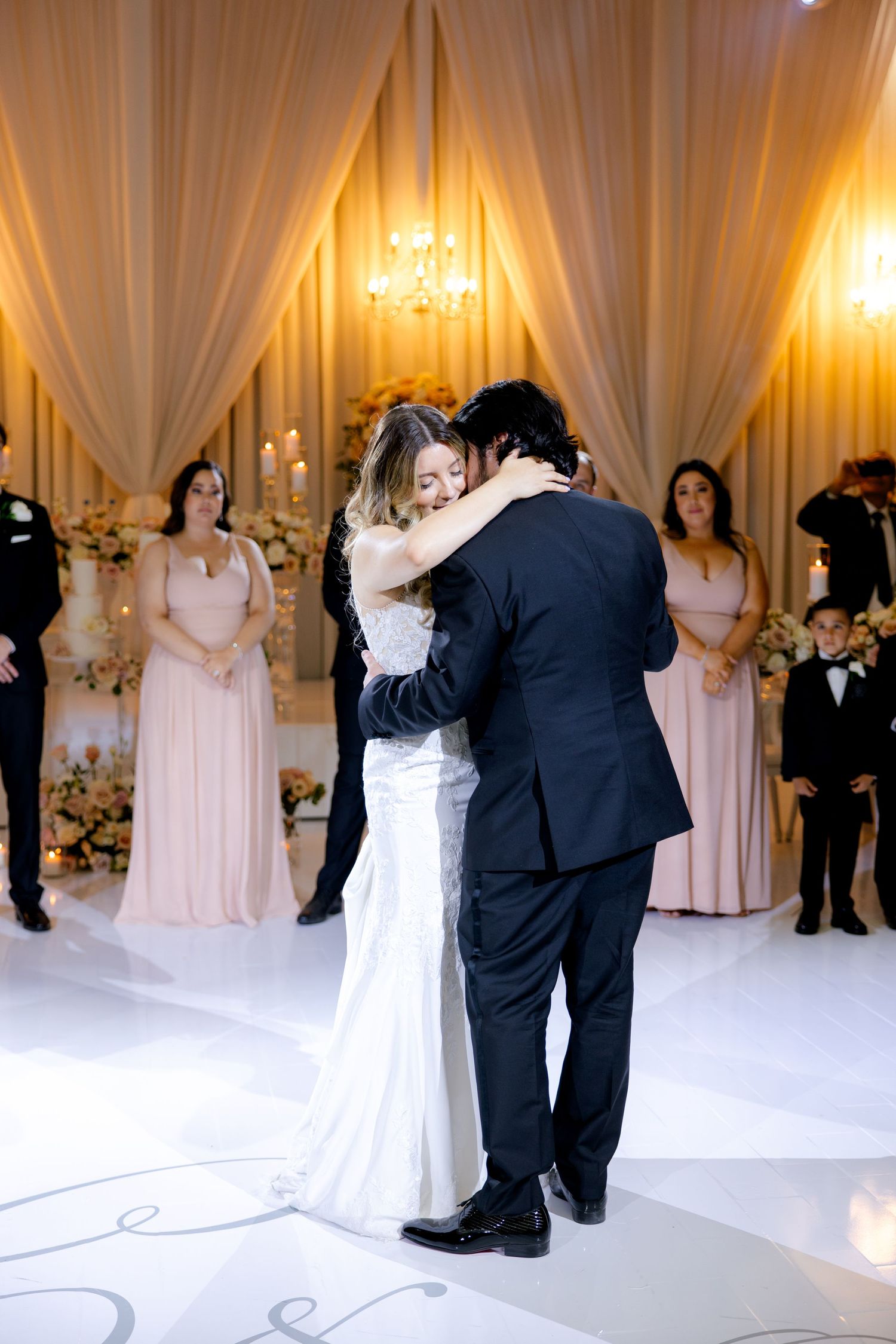 Romantic first dance moment in elegantly draped ballroom with soft lighting.
