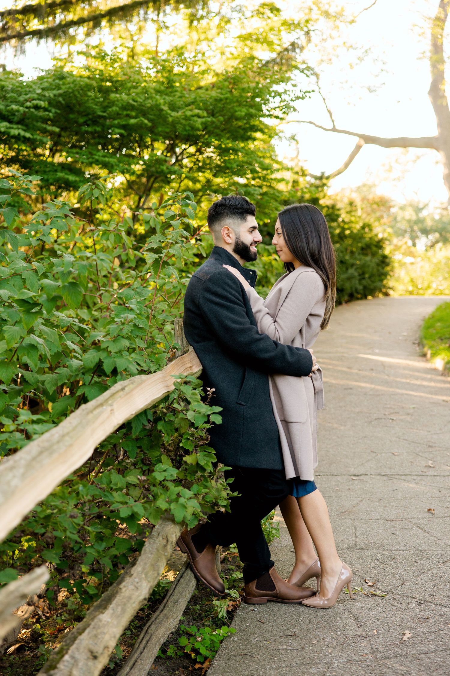 A couple shares an intimate moment along a garden path during sunset.